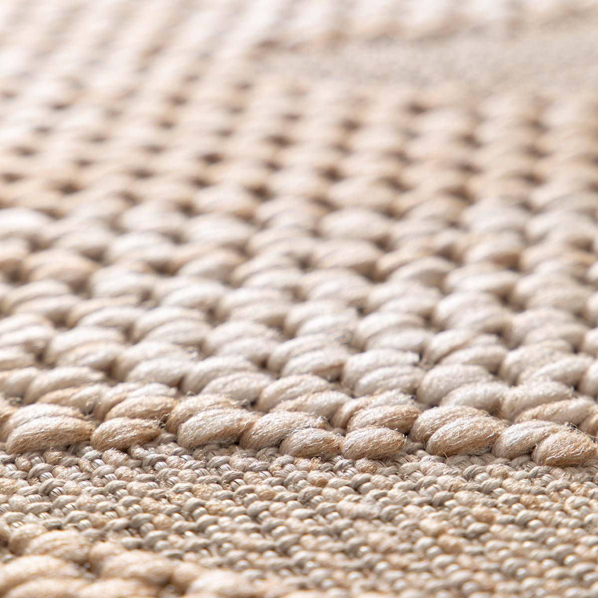 Close-up van een beige vloerkleed met zichtbare geweven textuur en draden.