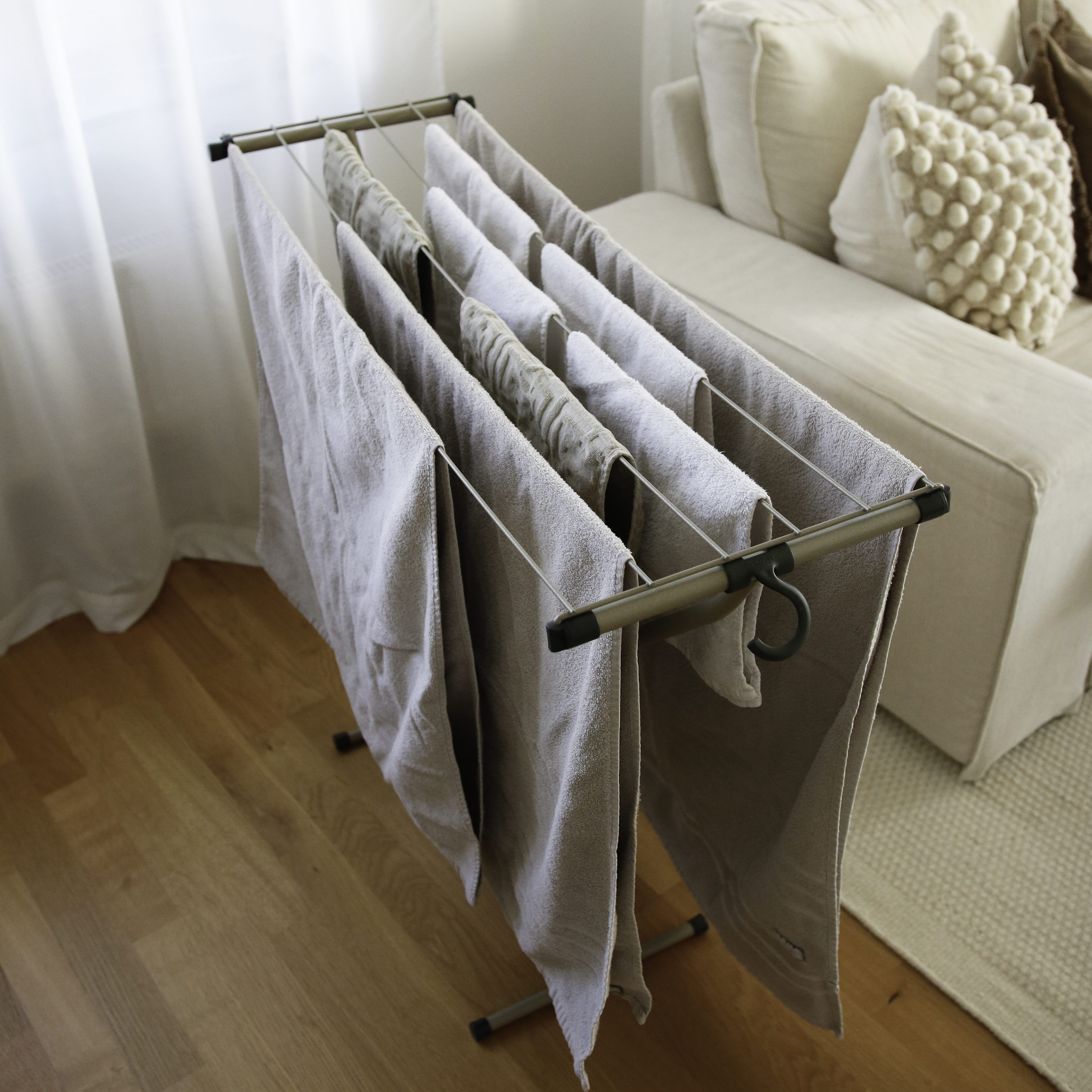 Un étendoir à linge avec des serviettes claires se dresse sur un plancher.