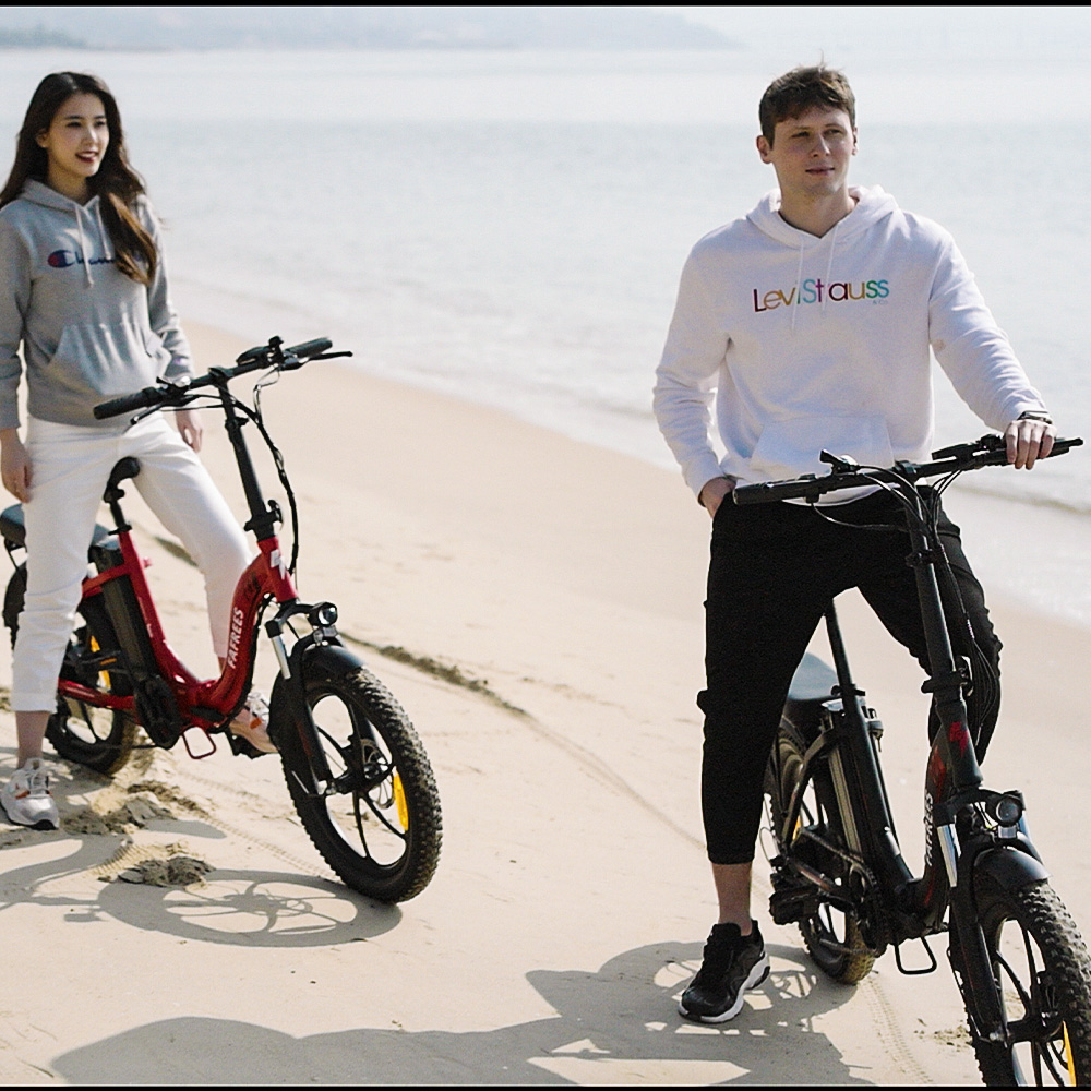 Mężczyzna i kobieta stoją z rowerami elektrycznymi na plaży.