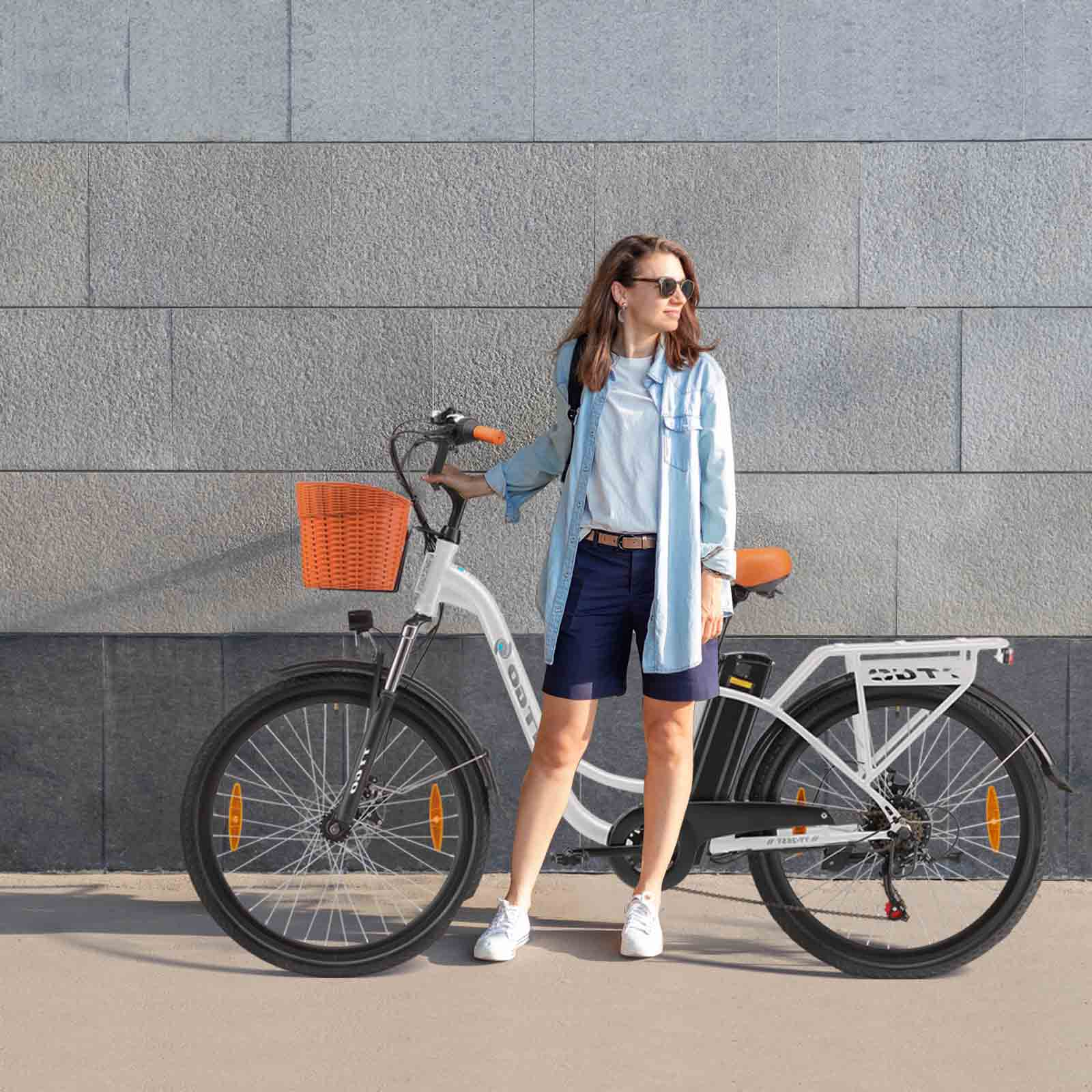 Eine Frau steht neben einem weißen E-Bike mit orangem Korb und Gepäckträger.