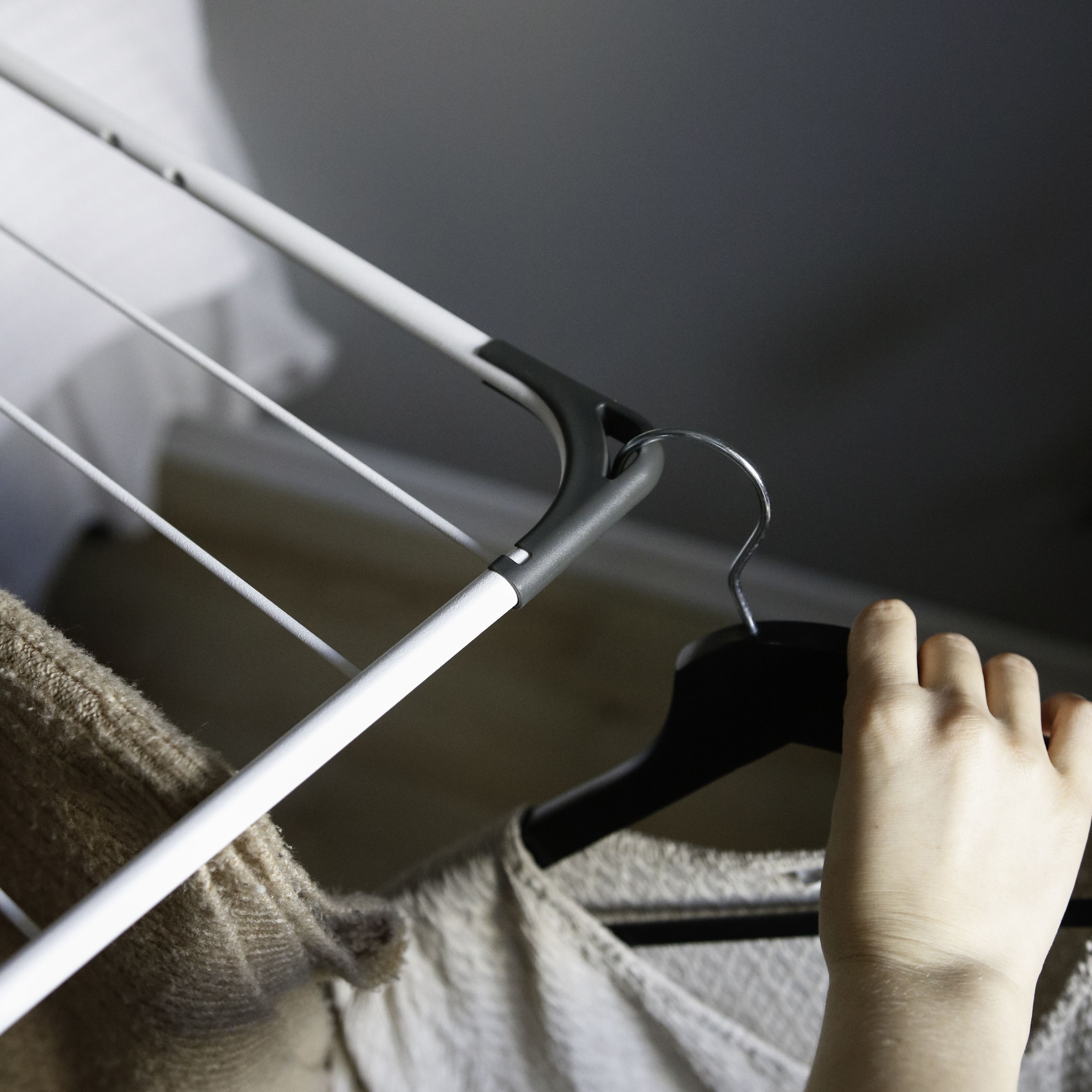 A hand hangs clothing on a drying rack.