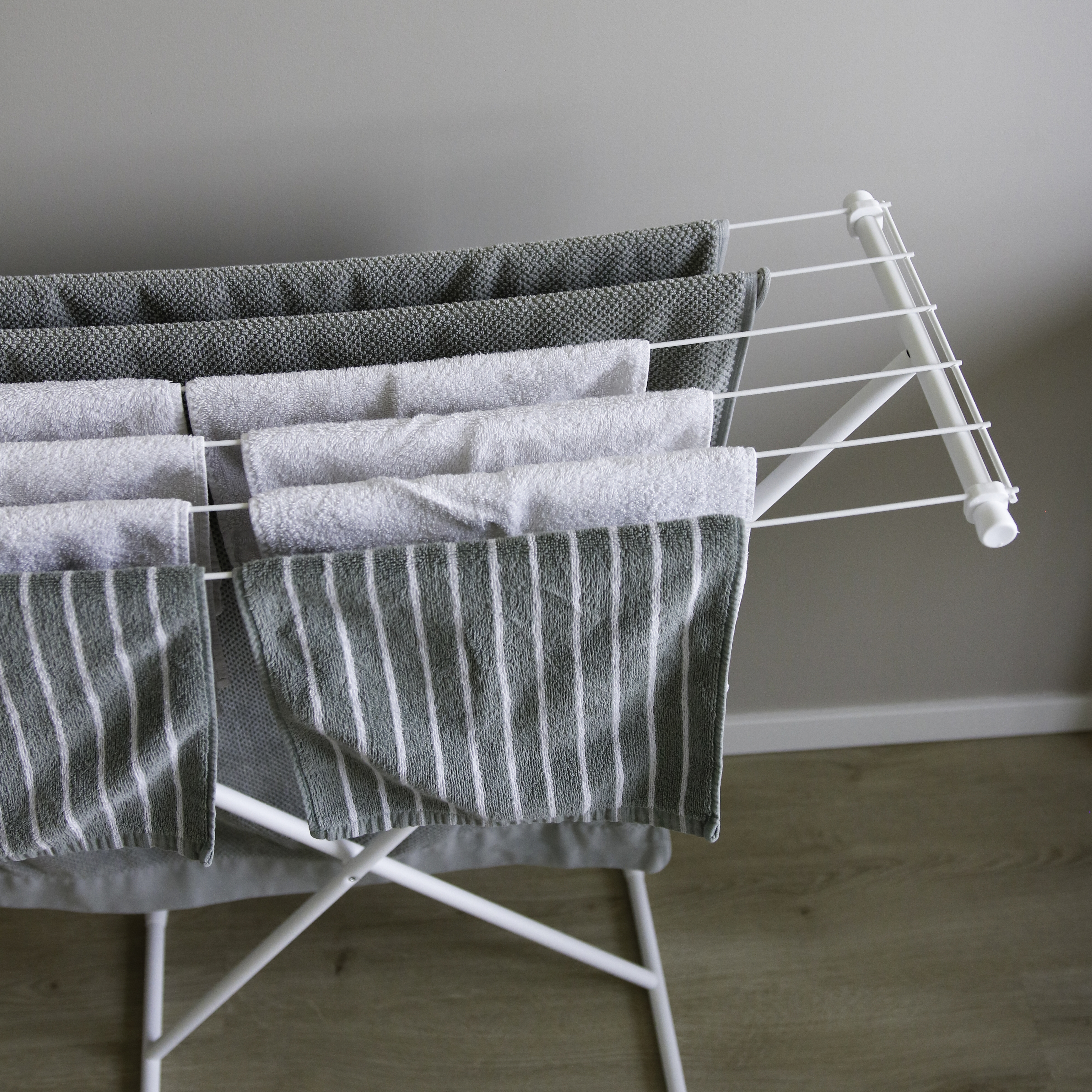 Un sèche-linge blanc avec plusieurs serviettes à motifs gris et blancs.