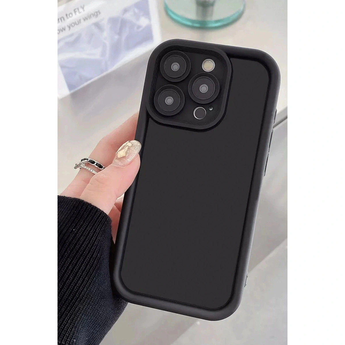 Dört kameralı siyah telefon kılıfı, takılı bir el tarafından tutuluyor.