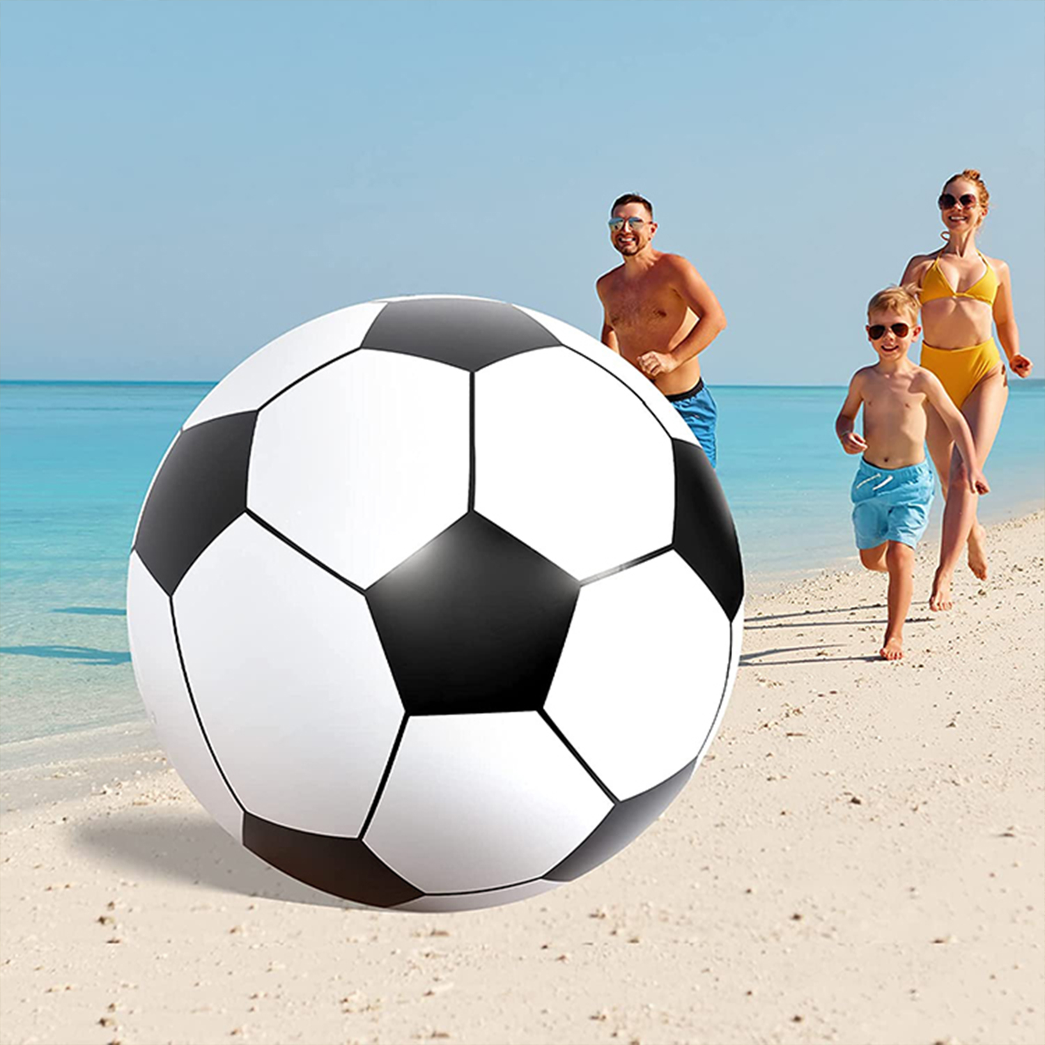 Balón de fútbol grande en la playa con una familia corriendo detrás.