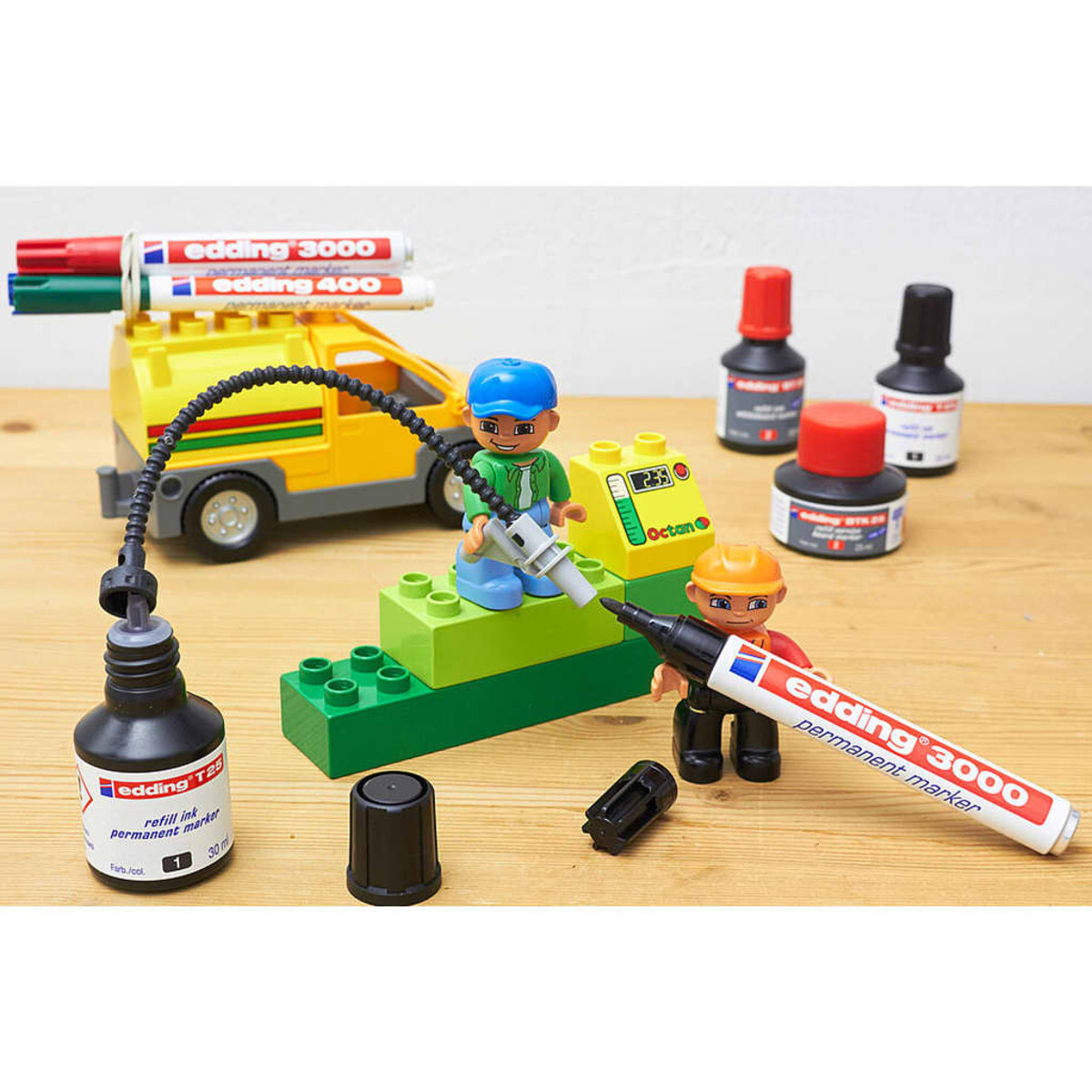 Spielzeugbausteine mit Figuren, einem Auto und Stiften auf einem Holztisch.