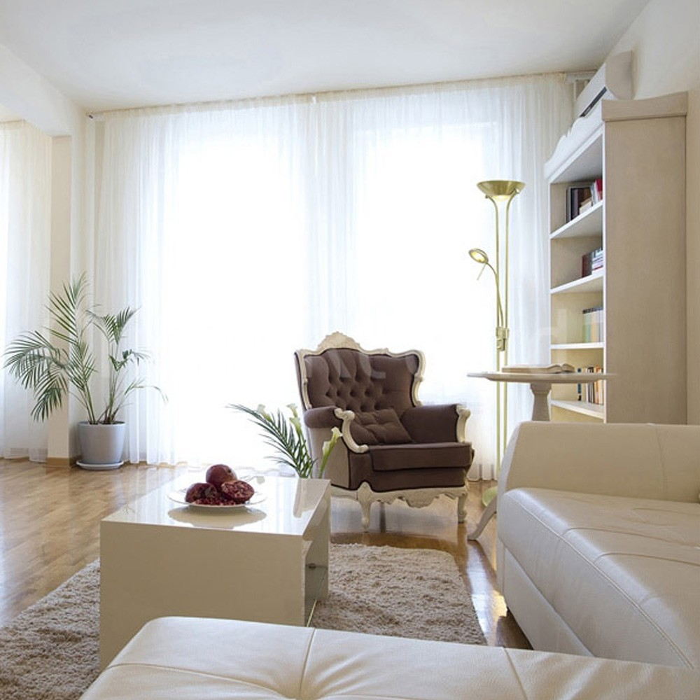 Un sillón marrón se sienta cerca de una estantería y una mesa blanca.
