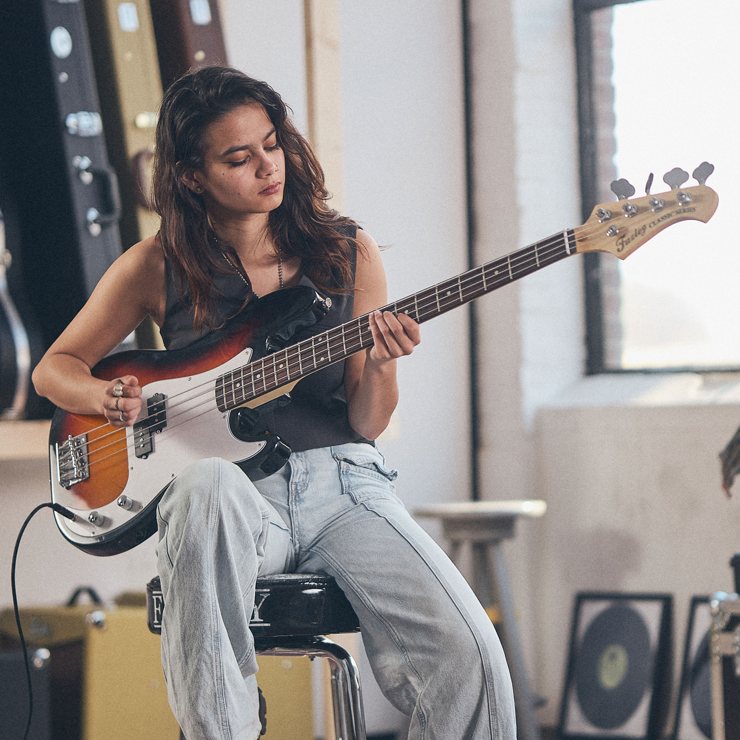 Een jonge vrouw speelt een elektrische basgitaar in een studio.