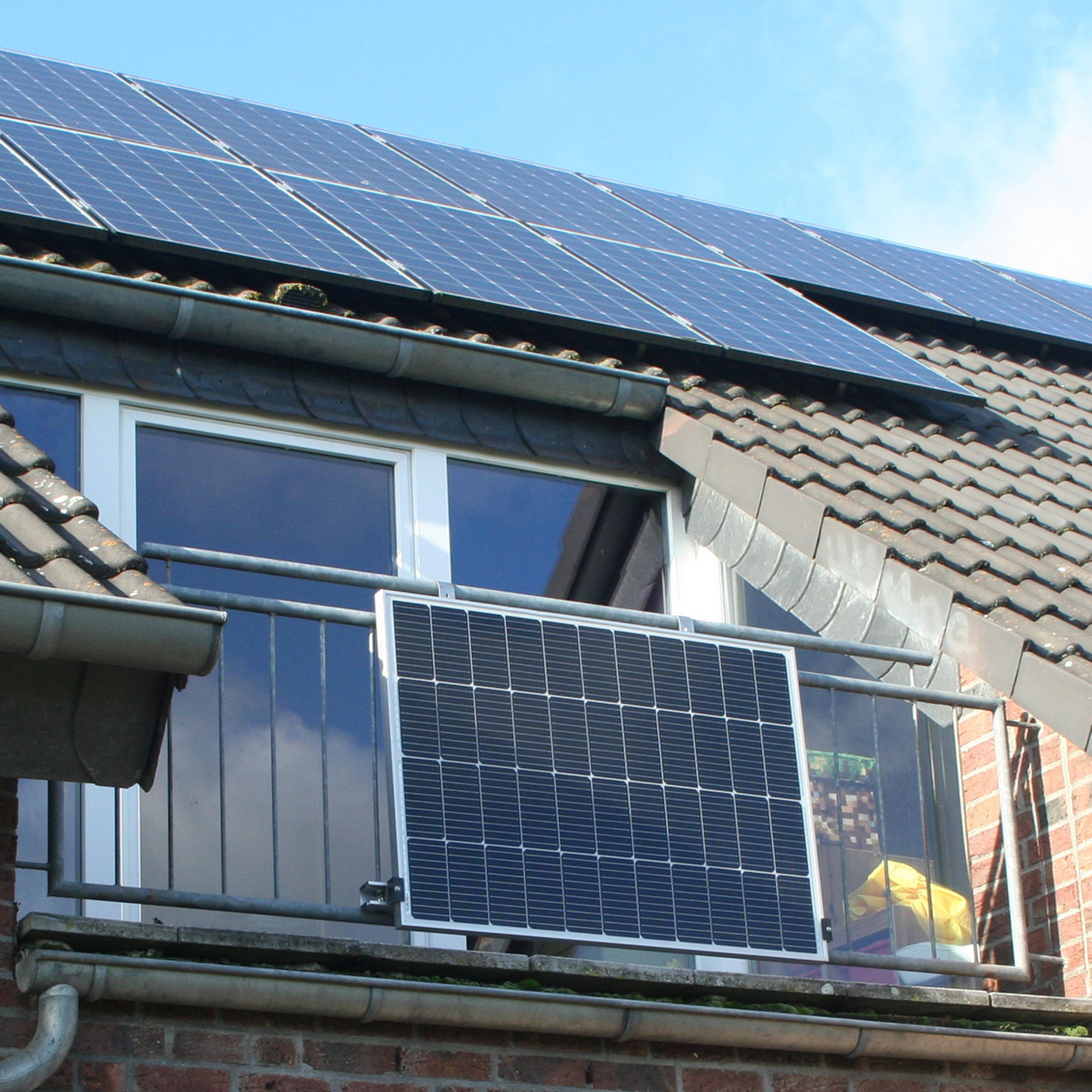 Solarmodule auf einem Dach, ein einzelnes Modul auf einem Balkon.