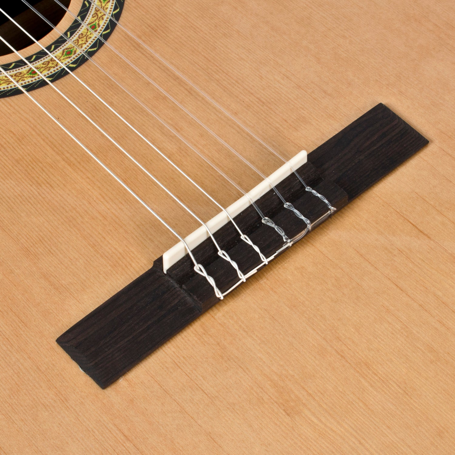 Close-up van een gitaarbrug en snaren op een houten klankbord.