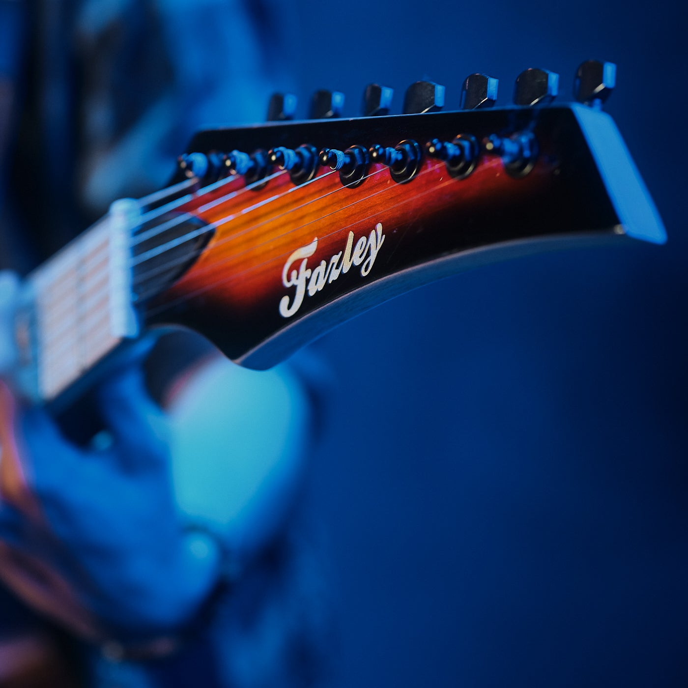 Close-up van een gitaarkop met stemmechanieken en sunburst afwerking.