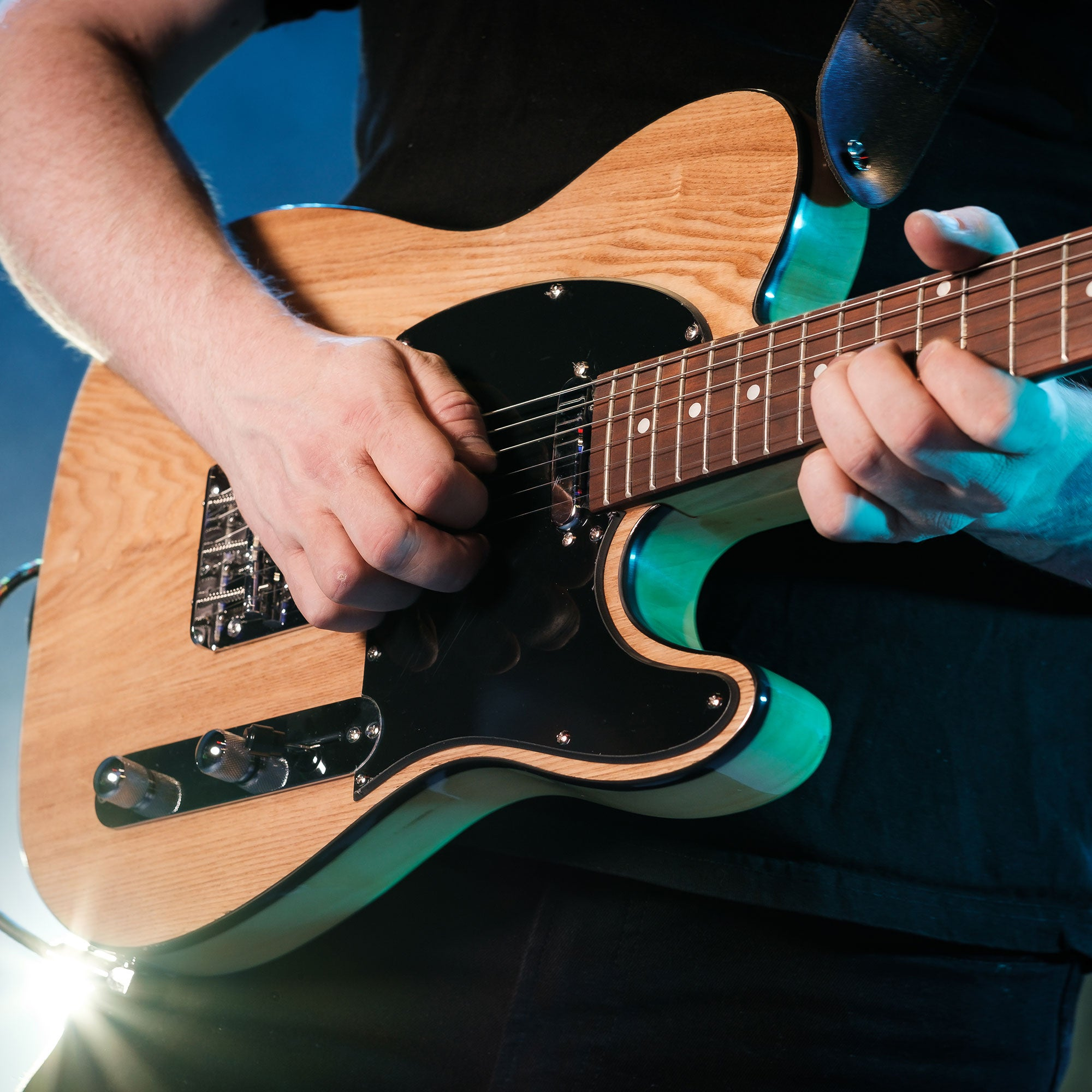 Een persoon bespeelt een licht houten gitaar met zwarte details.