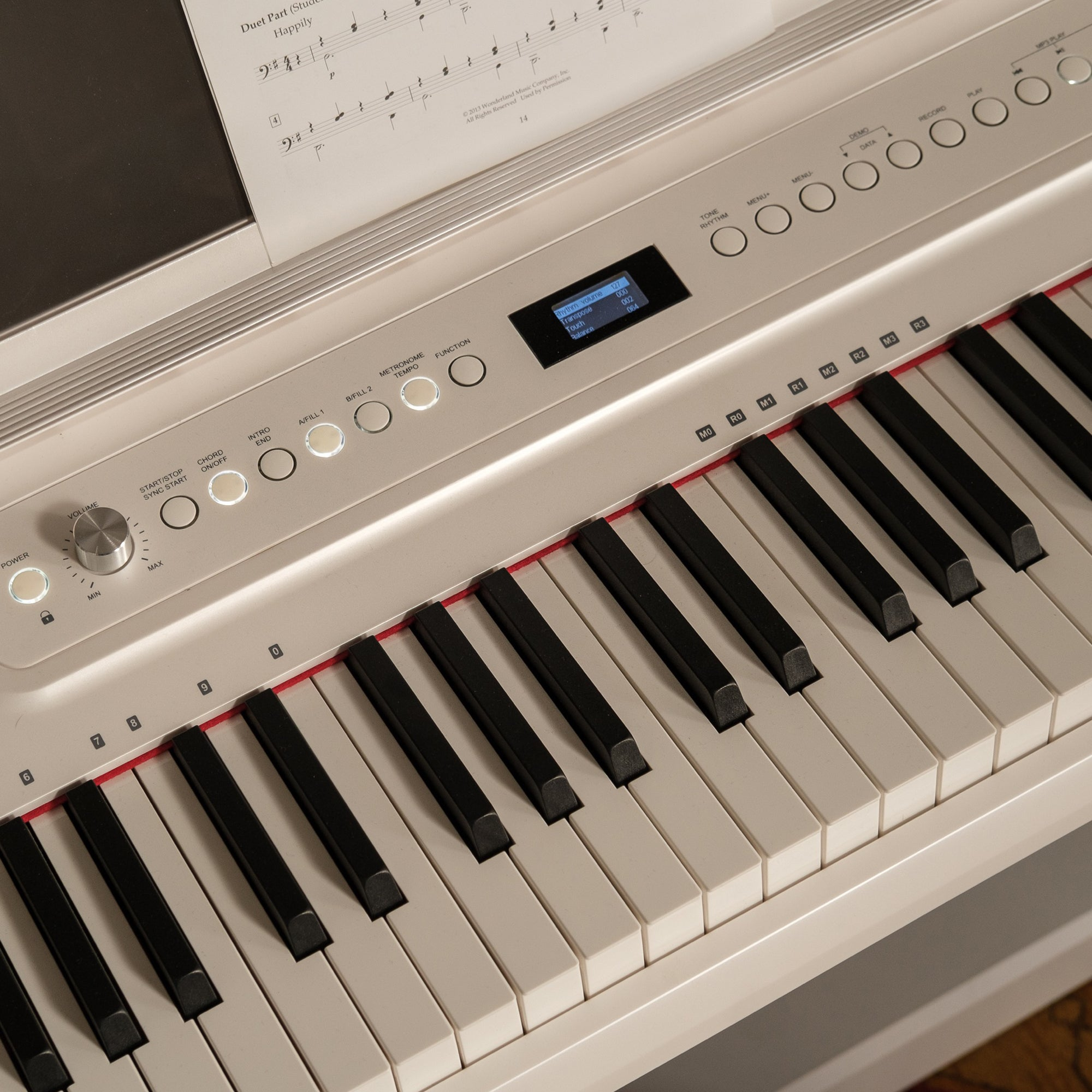 Close-up van een digitaal pianoklavier met bladmuziek en bedieningspaneel.