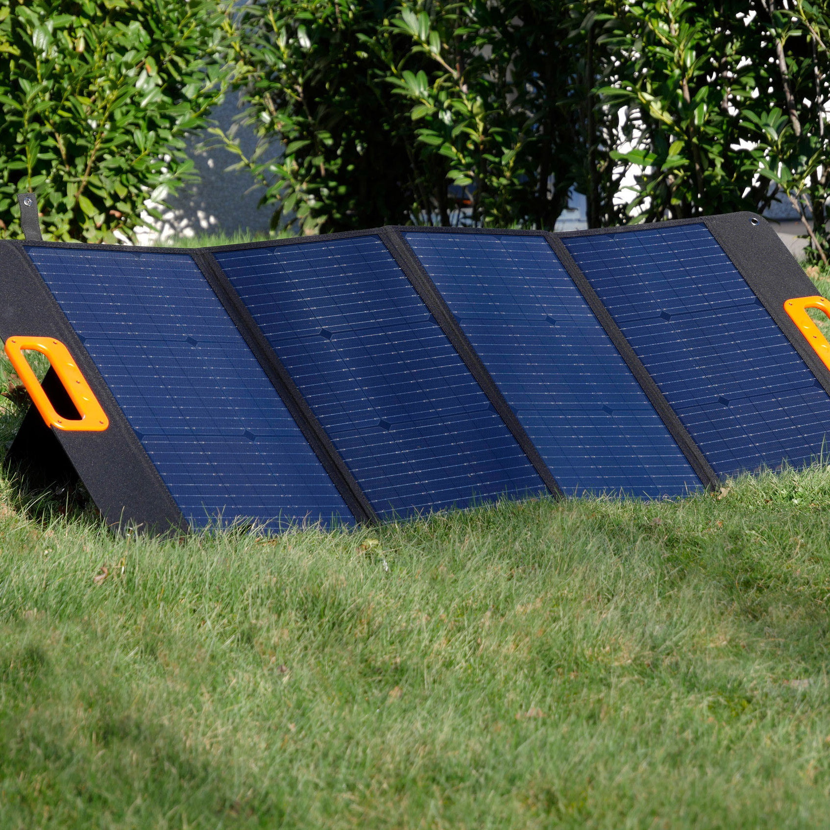 Ein aufgestelltes Solarpanel mit vier blauen Segmenten steht auf grünem Gras.