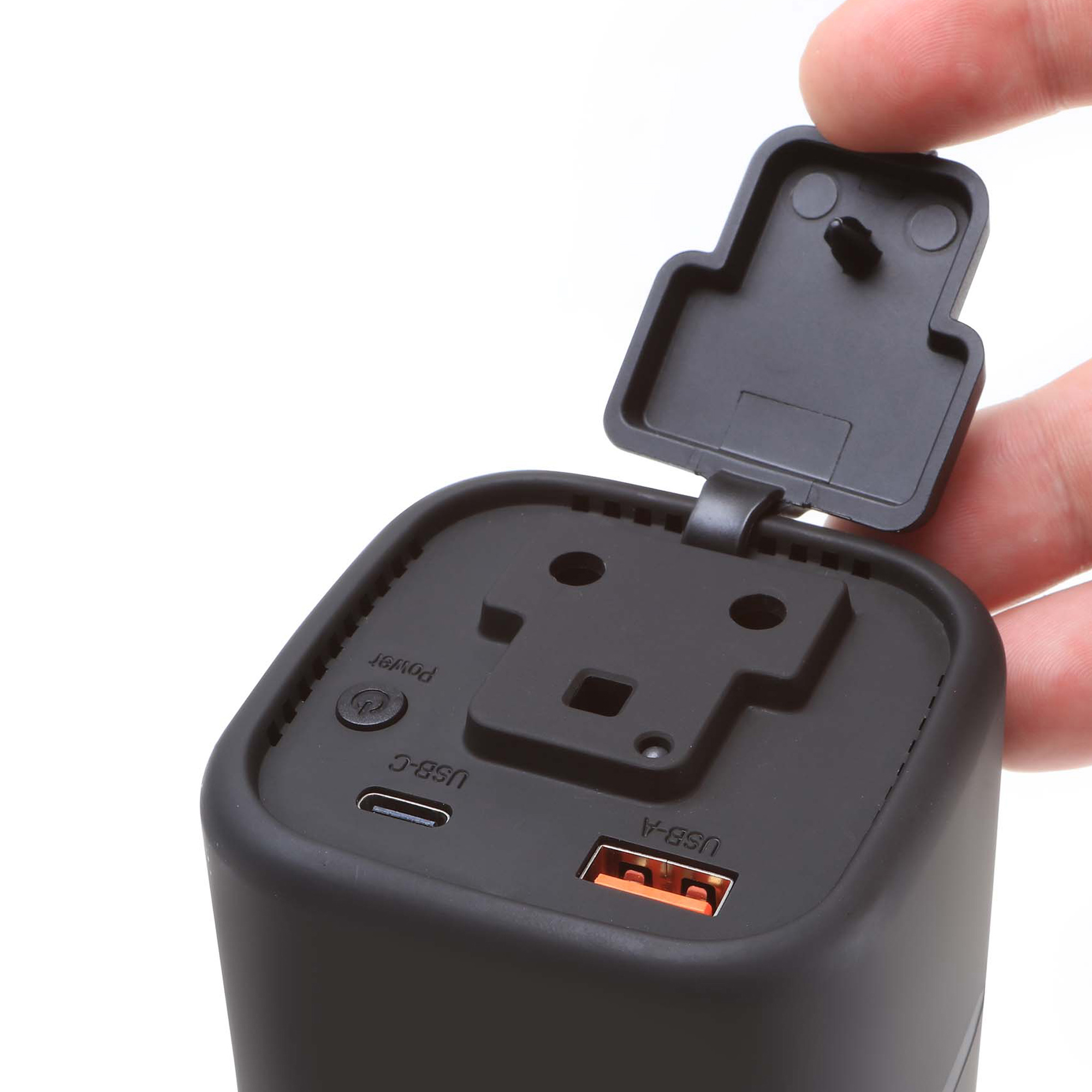 Eine Hand öffnet eine schwarze Klappe über einem schwarzen Ladegerät mit USB-Anschlüssen.
