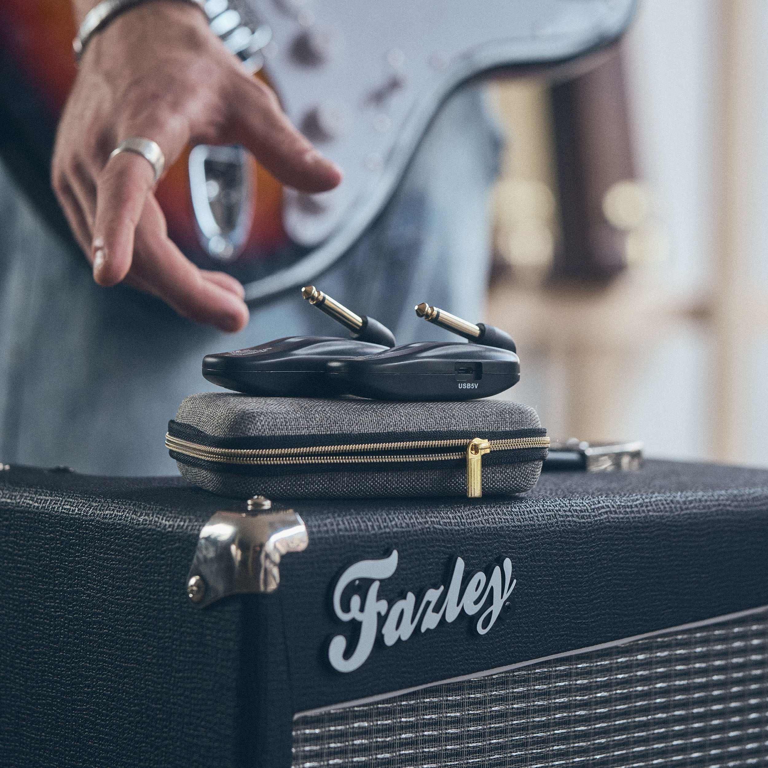 Een man speelt gitaar naast een gitaartransmitter en versterker.