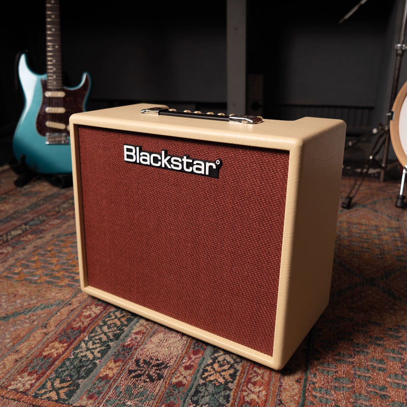 Een beige Blackstar gitaarversterker met rood rooster staat op een kleed.