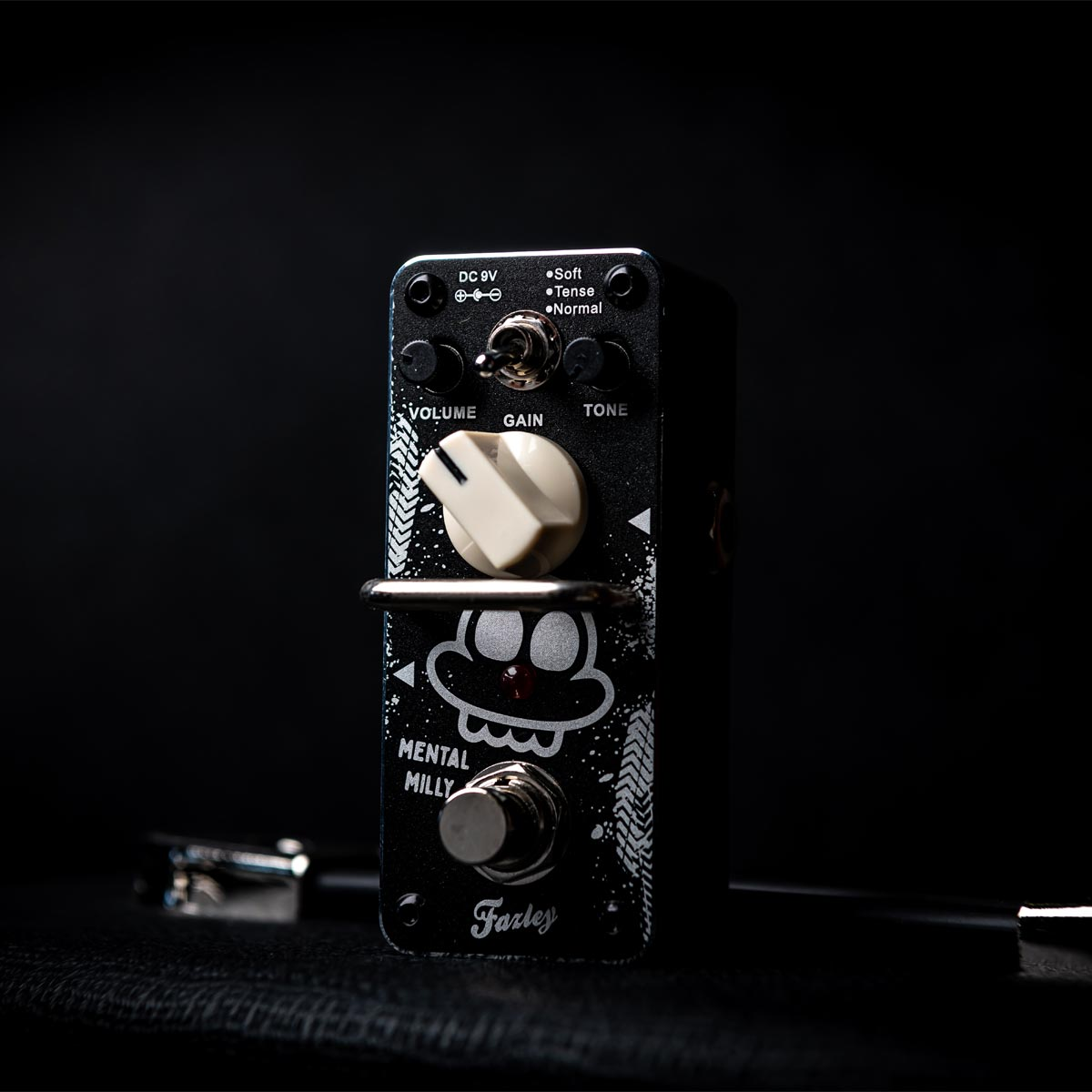 A black guitar effects pedal with a white knob and switch.