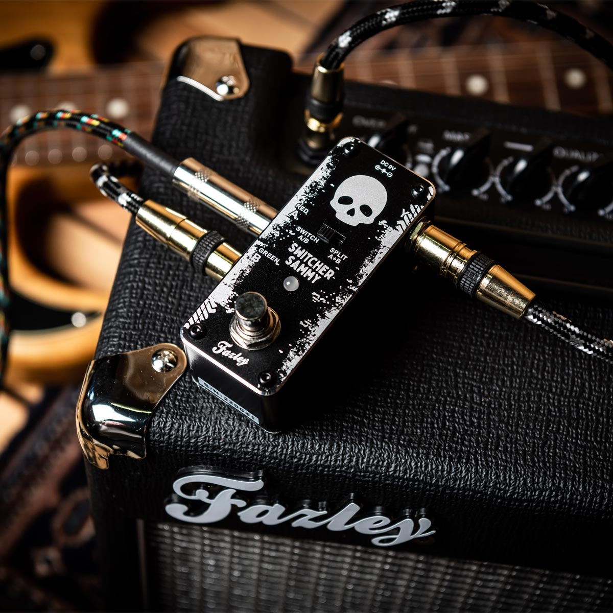 A black guitar effect pedal with a skull graphic sits on a black amplifier.