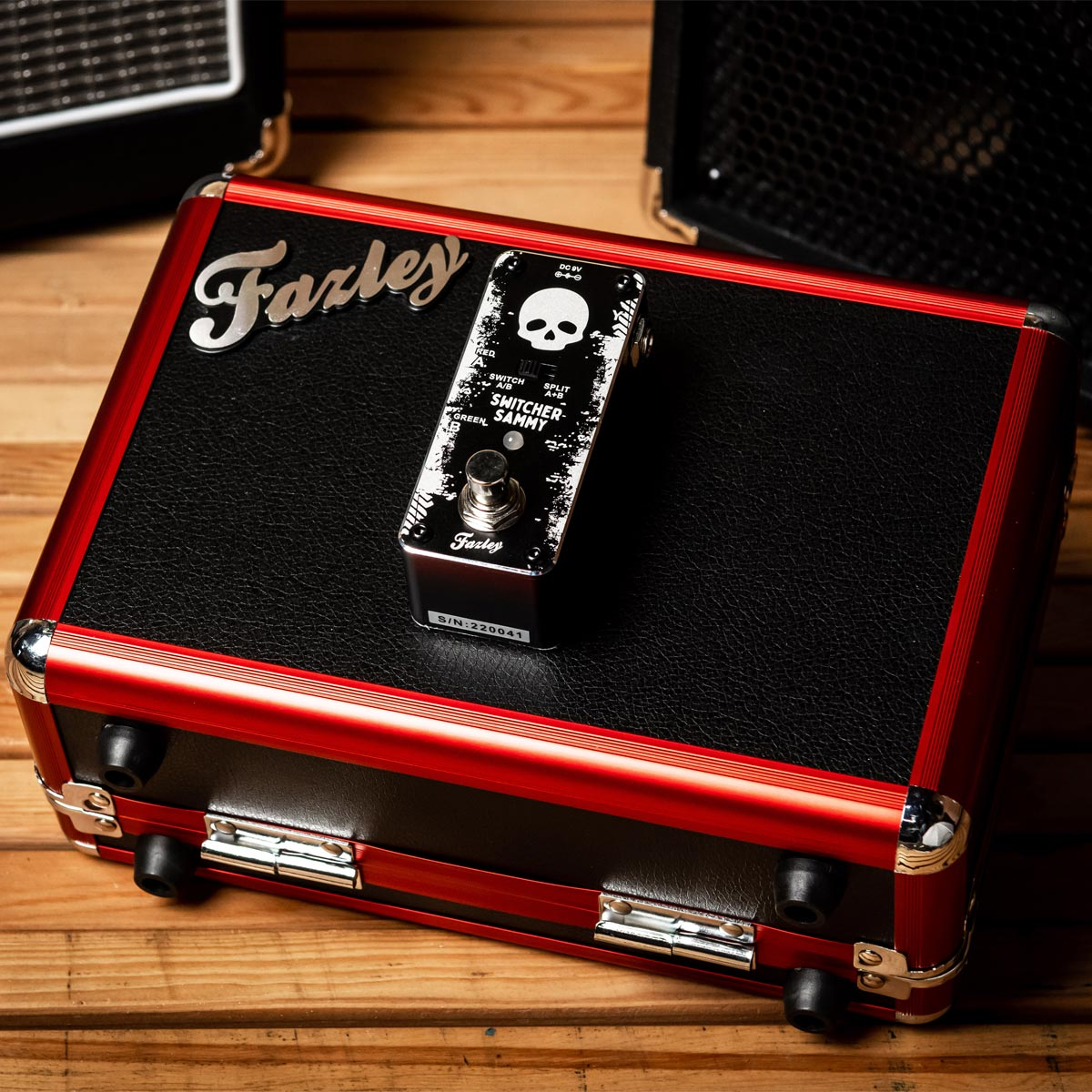 A red guitar effect pedal case with a black top and a skull pedal on it.