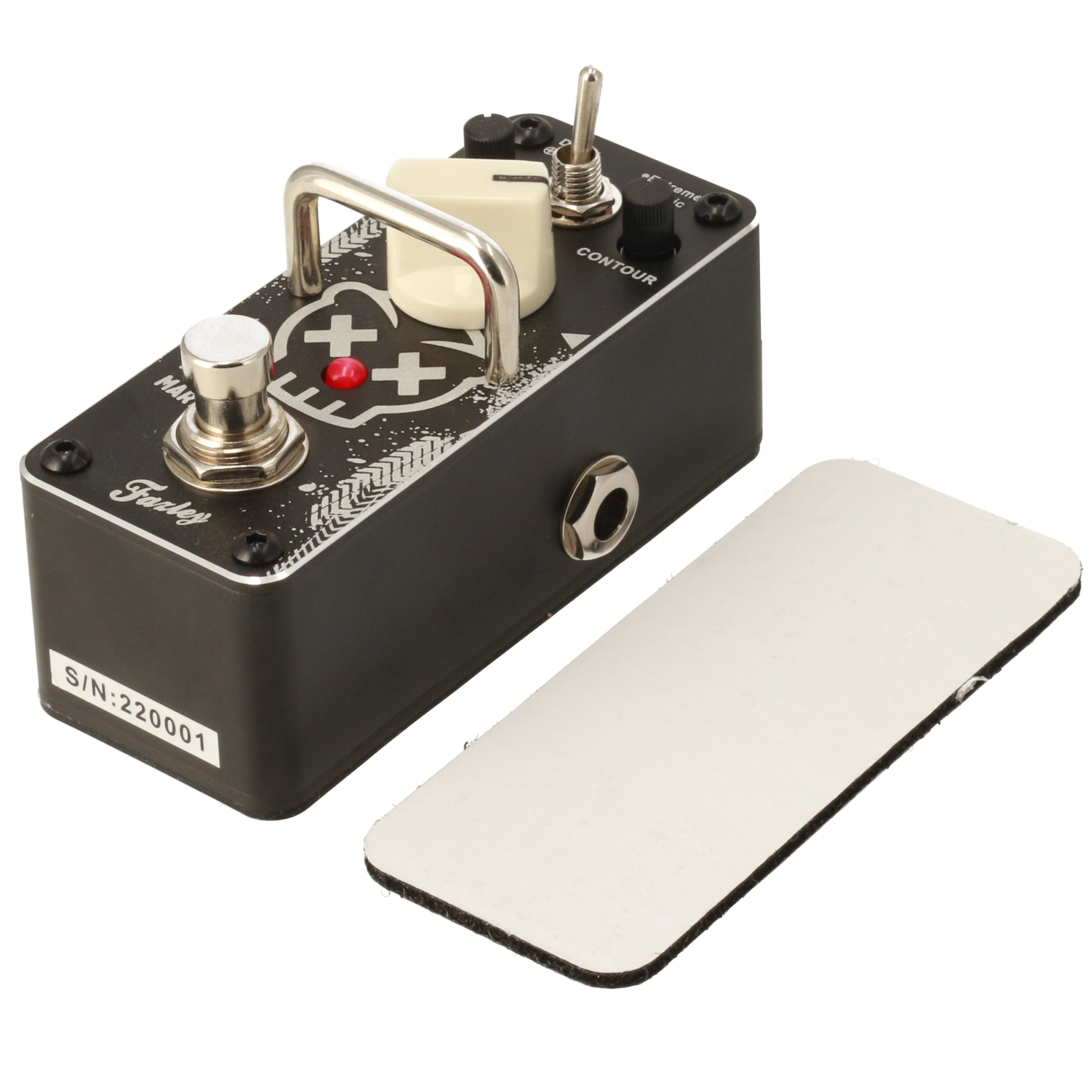 Black guitar effect pedal with silver switch and knob. White plate beside it.