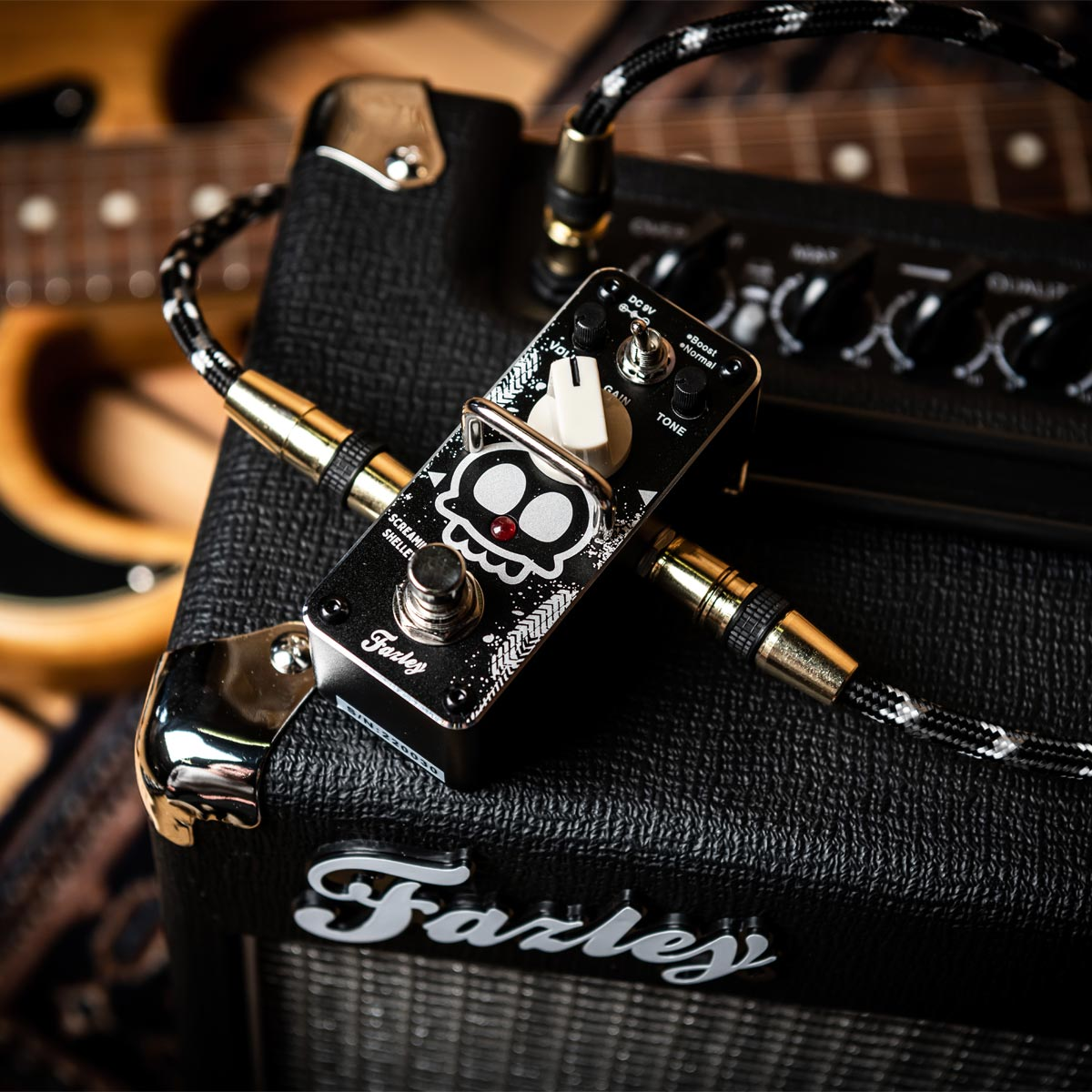A black guitar amp with a distortion pedal and cables.
