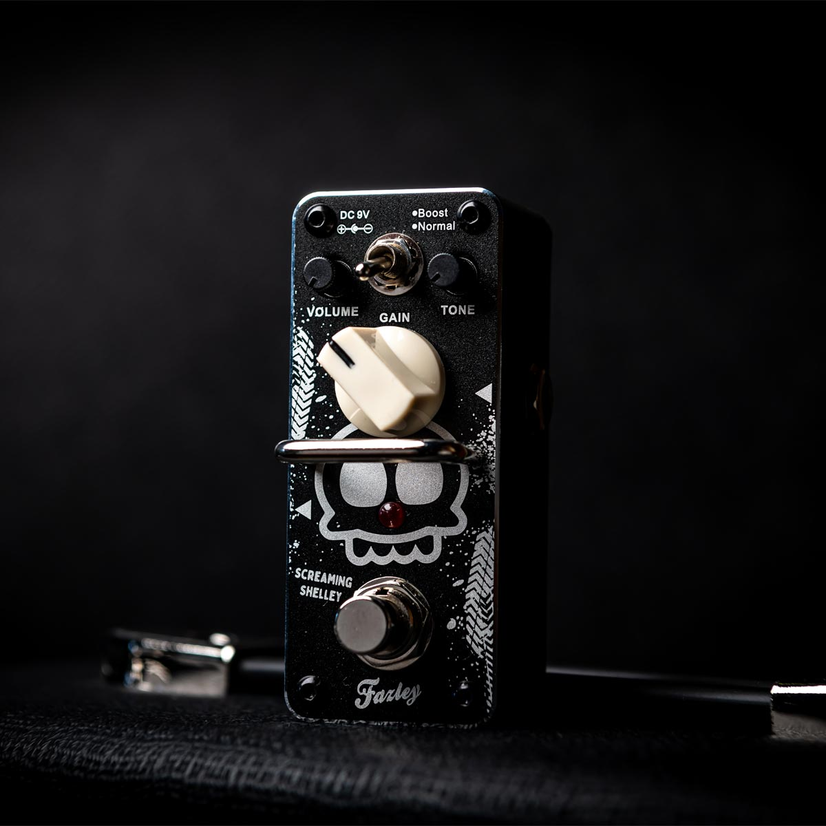 A black guitar effects pedal with a skull design, a large white knob, and a silver footswitch.