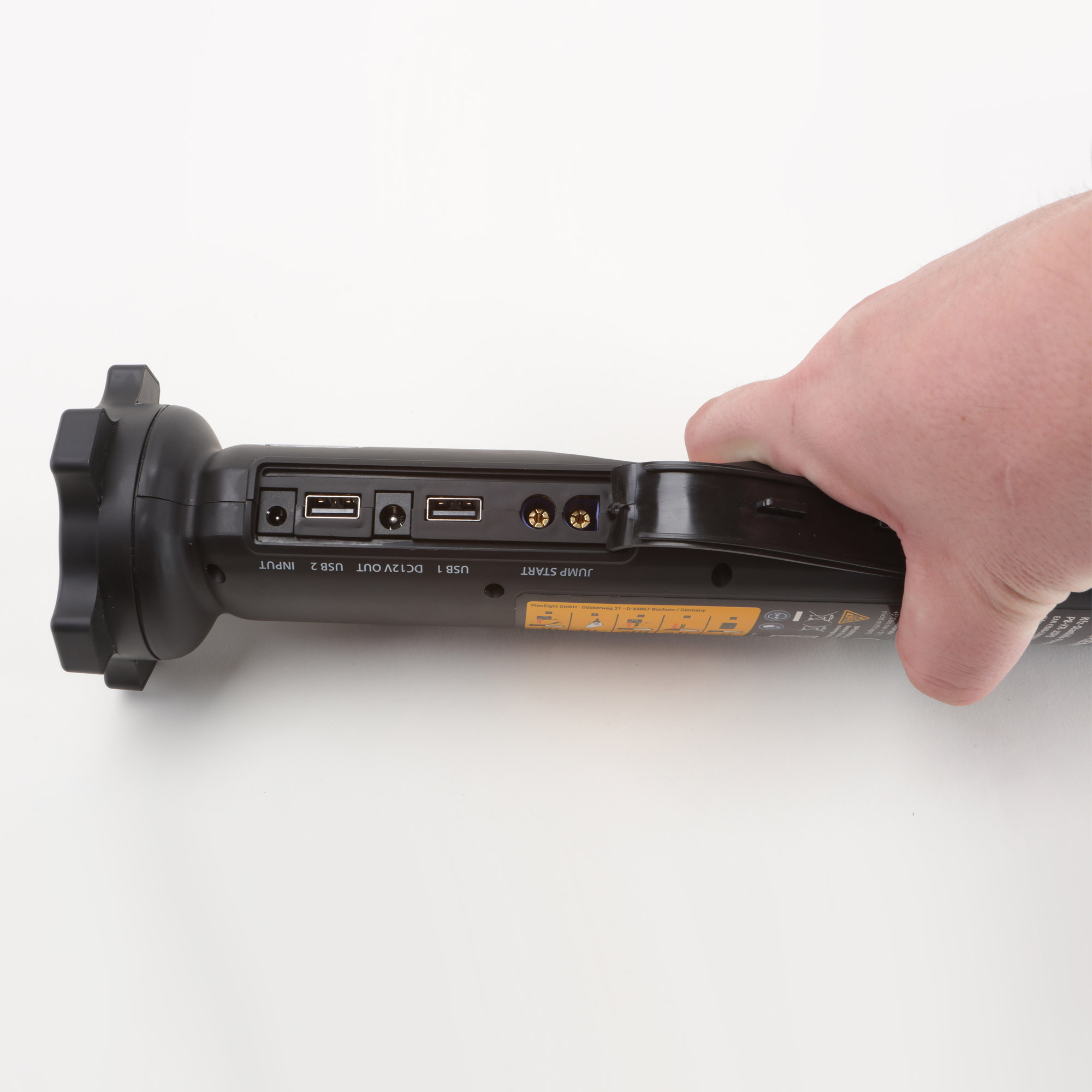 Hand hält schwarzes Starthilfegerät mit USB-Anschlüssen und Beschriftung.
