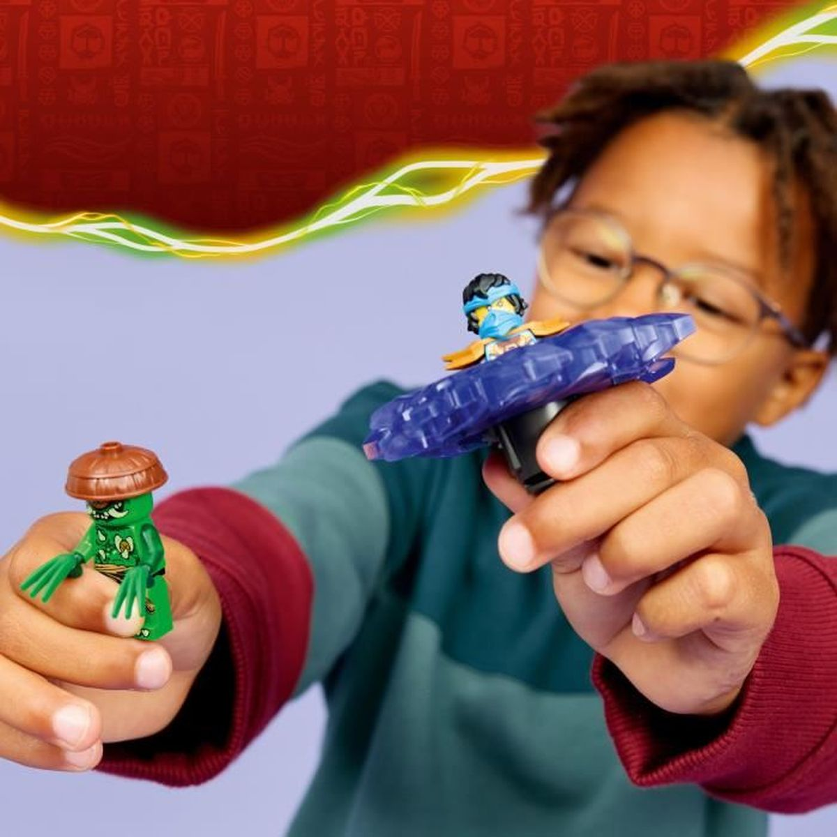 Un ragazzo tiene una figura verde e una trottola blu con un personaggio.