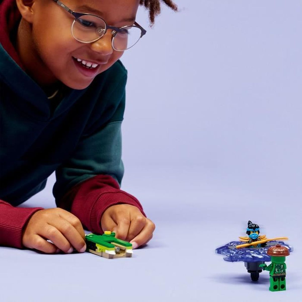 Un ragazzo con gli occhiali gioca con personaggi LEGO e un giocattolo coccodrillo.