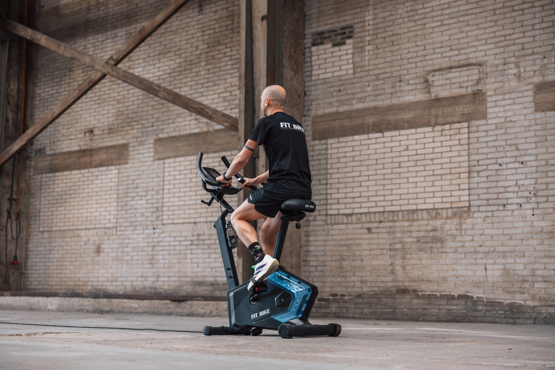 Man op zwarte hometrainer in bakstenen gebouw.