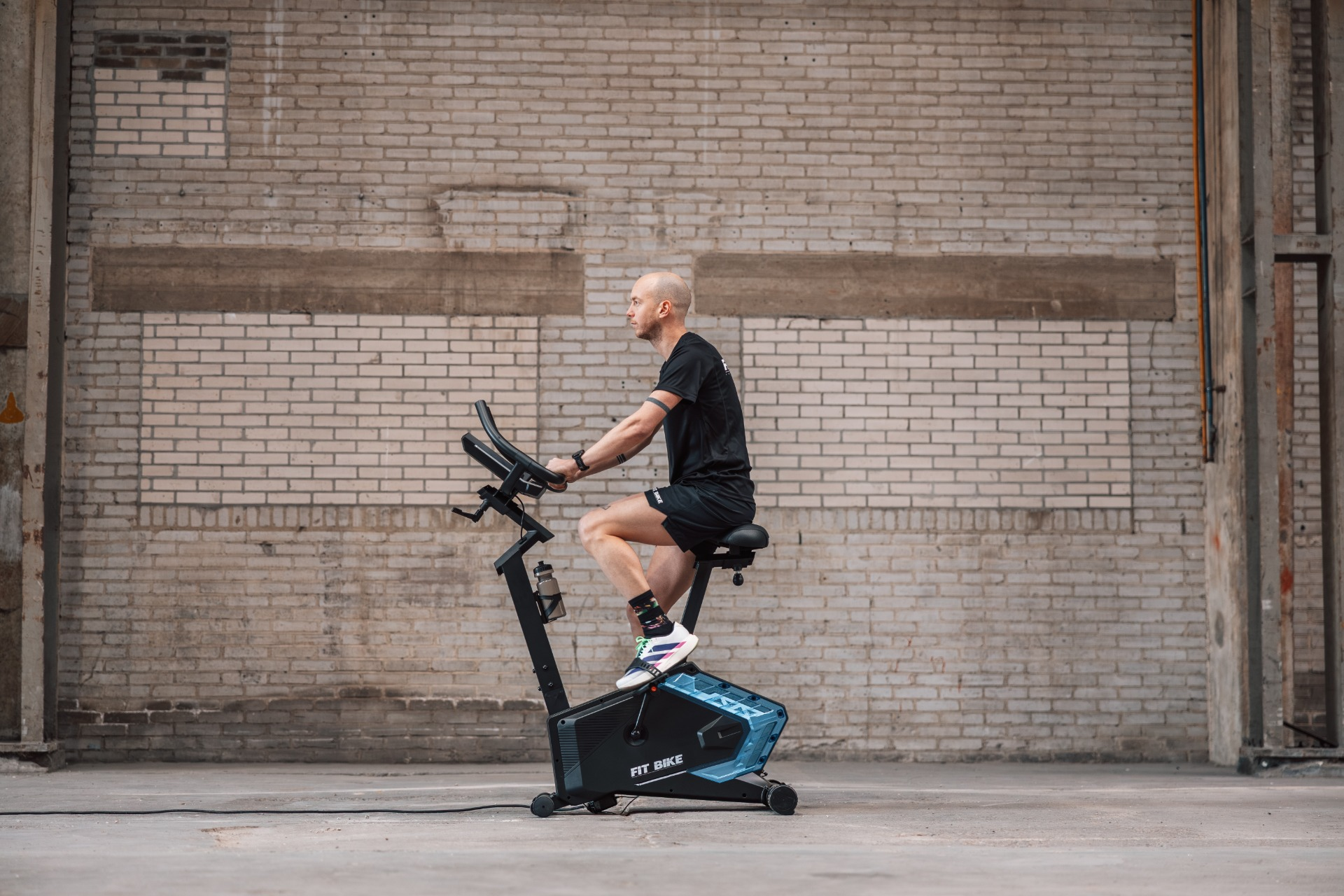 Man traint op hometrainer voor bakstenen muur.