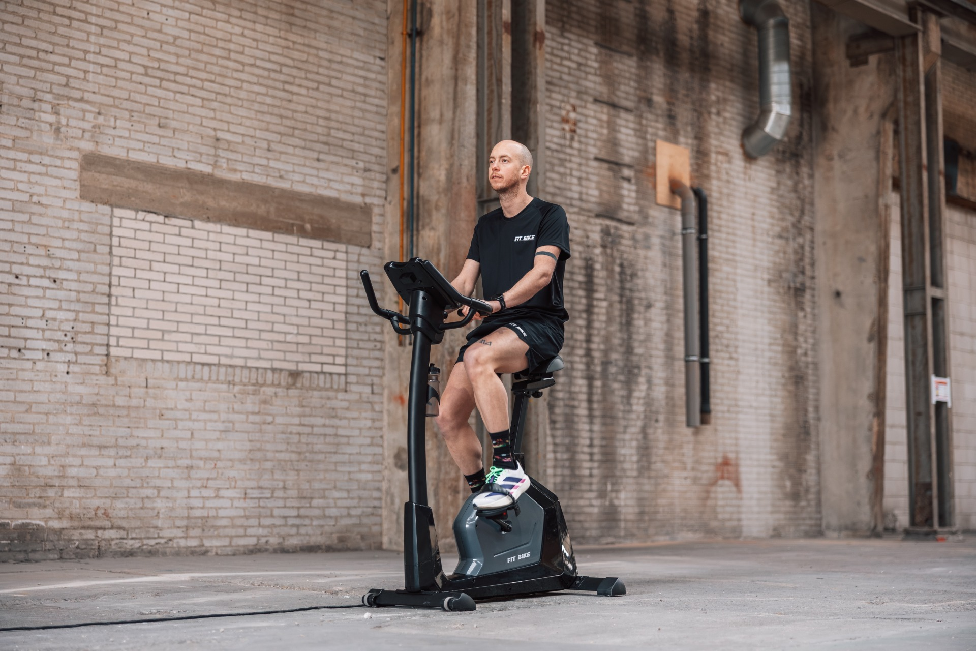 Un homme fait du vélo d'appartement dans un espace industriel.