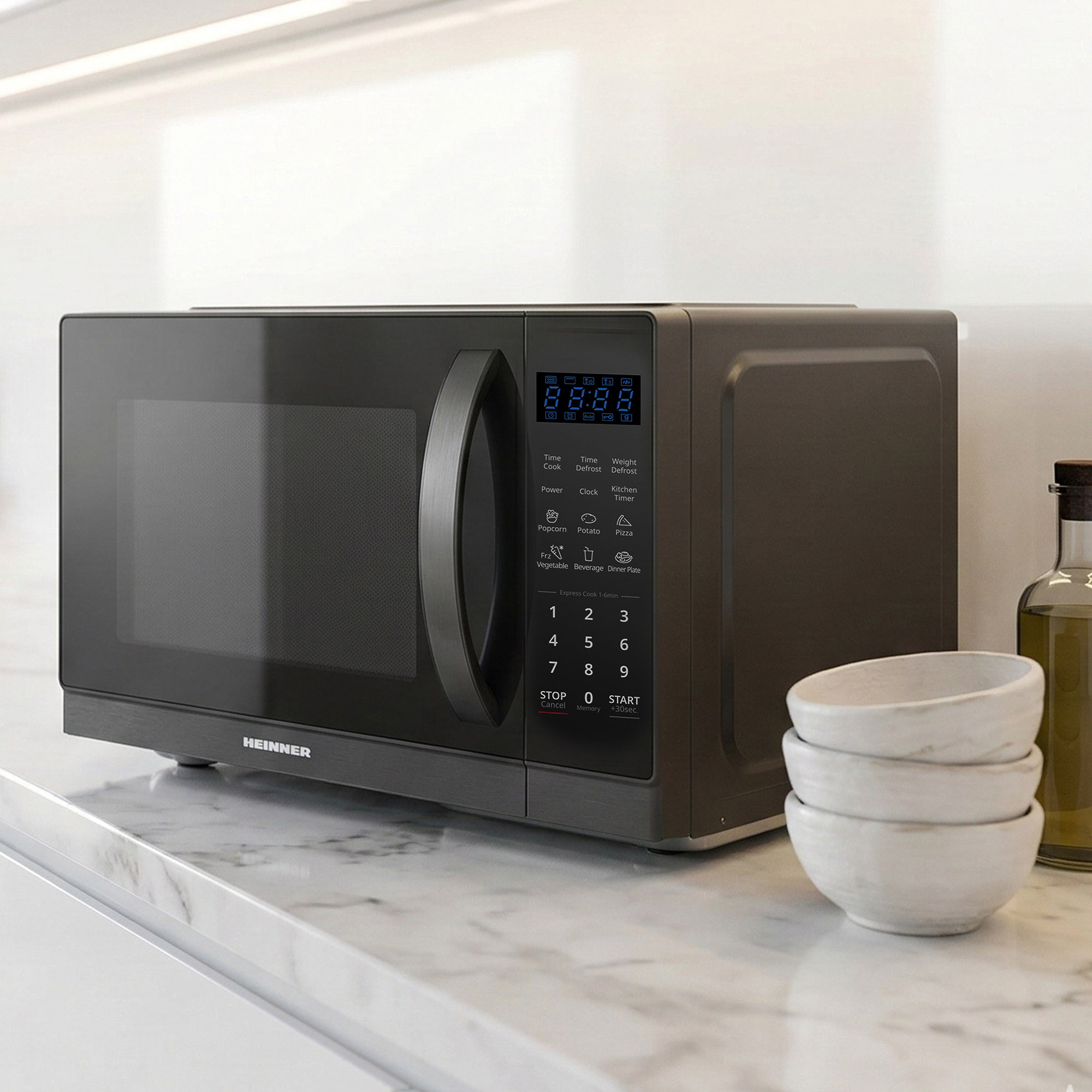 Dark gray microwave with digital display and controls on a marble countertop.