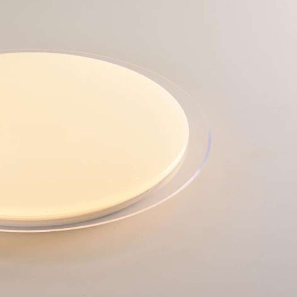 Una lámpara redonda de color crema con borde transparente sobre fondo claro.