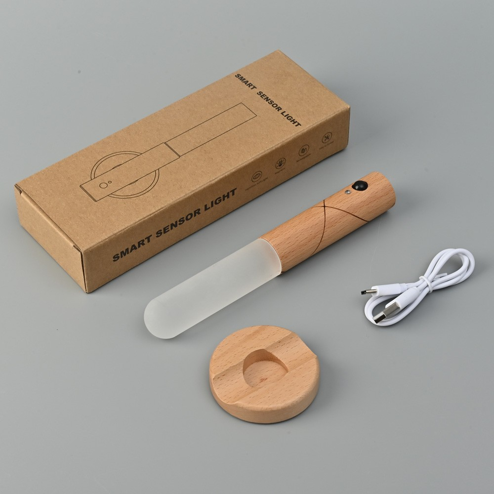 Una luz con sensor inteligente con detalles de madera, cable de carga y caja.
