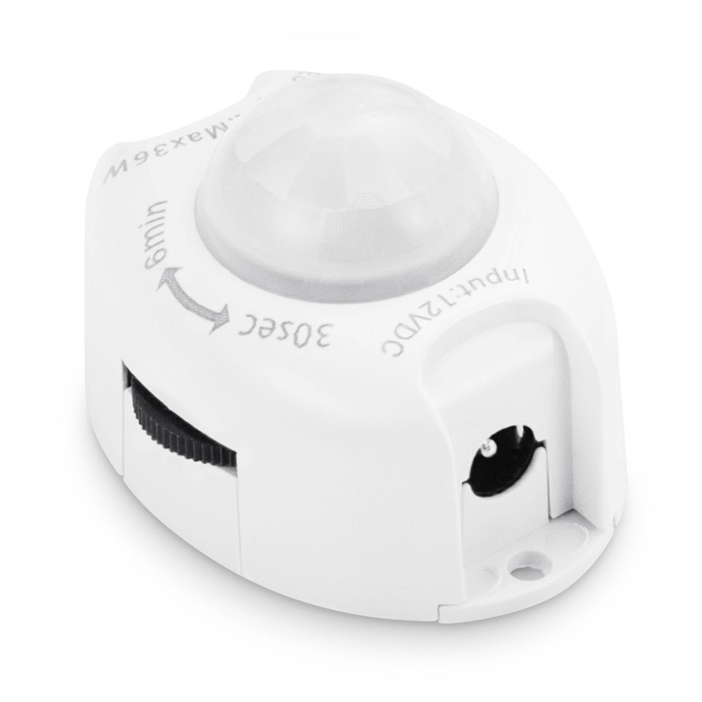 Un sensor de movimiento blanco con cubierta de lente y diales para tiempo y sensibilidad.