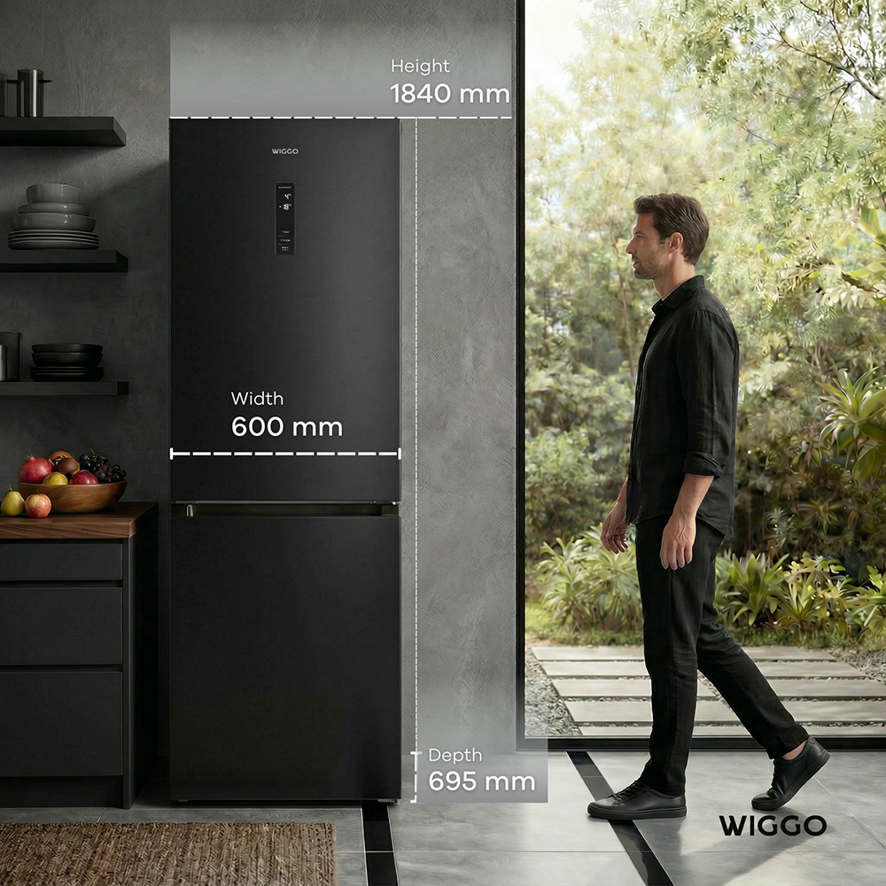 A man in a black shirt stands beside a black refrigerator with dimensions.