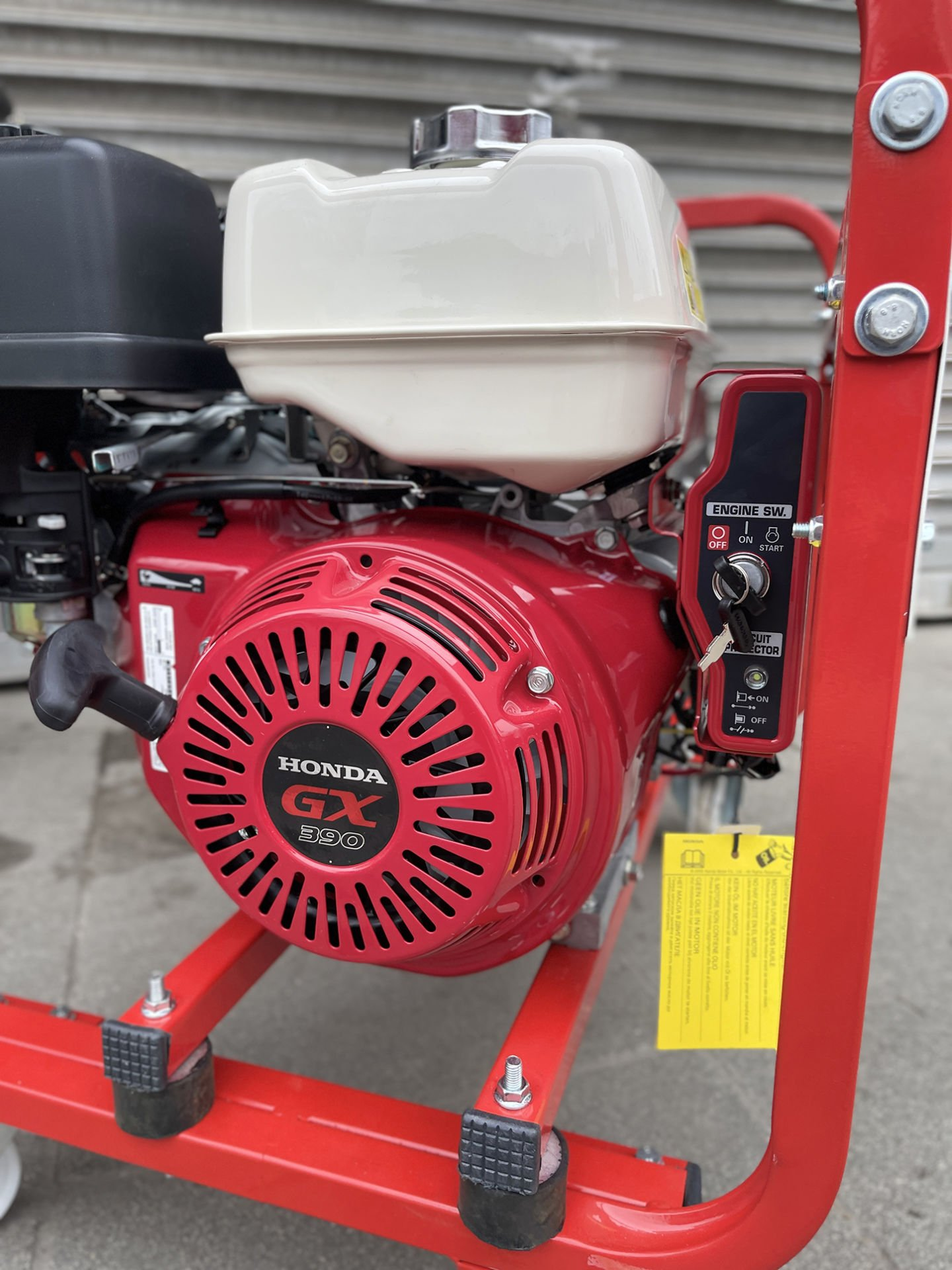 Beyaz yakıt deposu ve siyah hava filtresine sahip kırmızı Honda GX390 jeneratör.