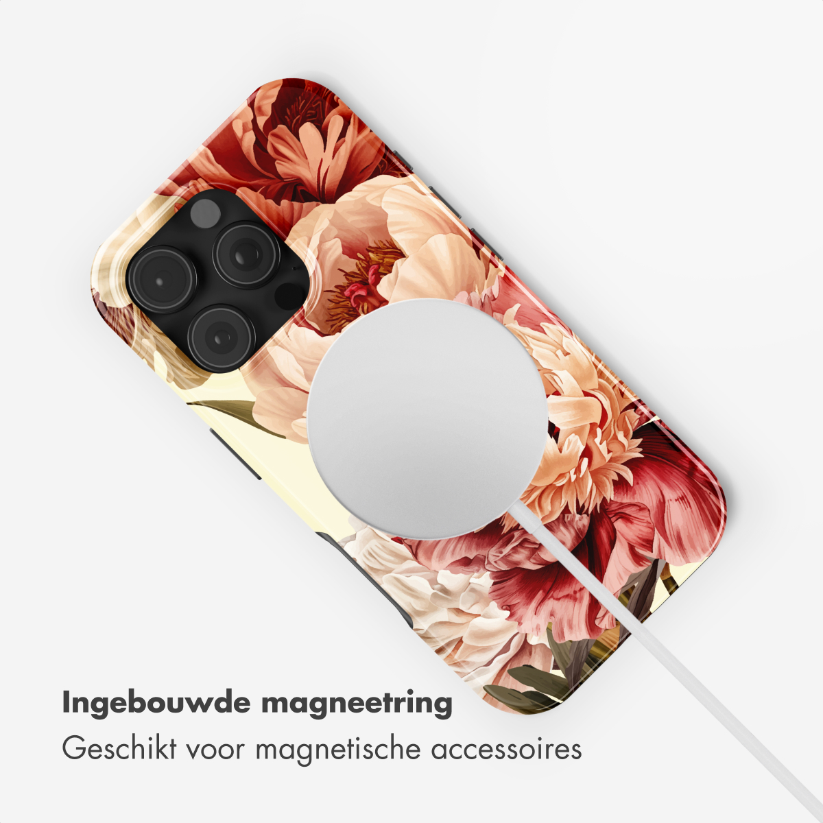 Una cover per telefono con motivo floreale giace su una superficie bianca con un cavo.