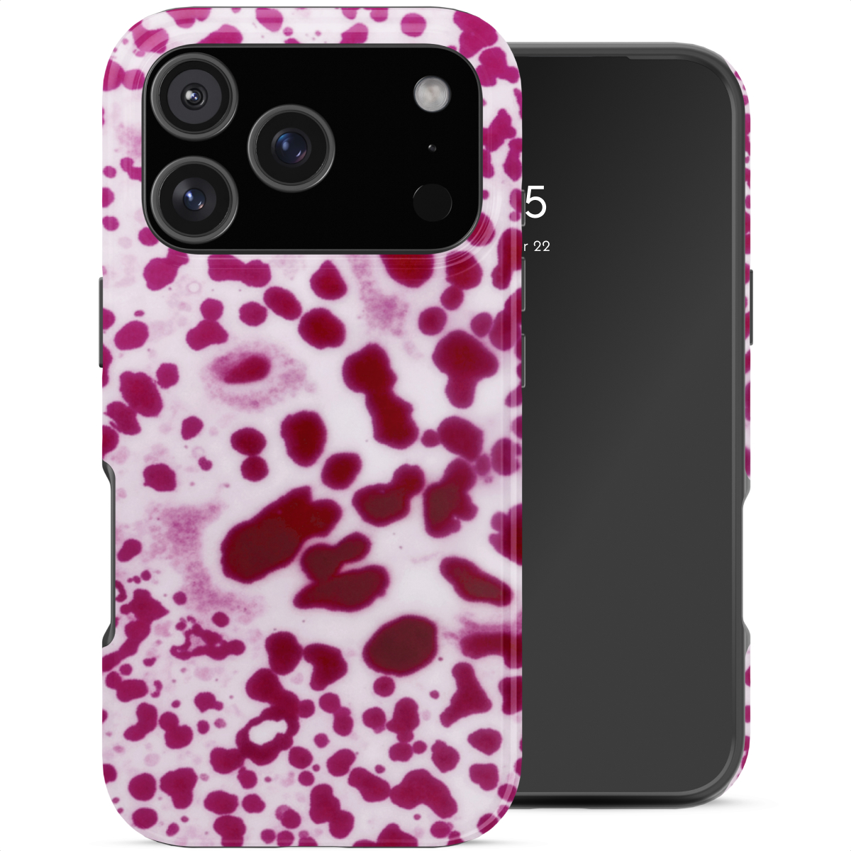 Een roze en witte gespikkelde telefoonhoes naast een zwarte telefoon.