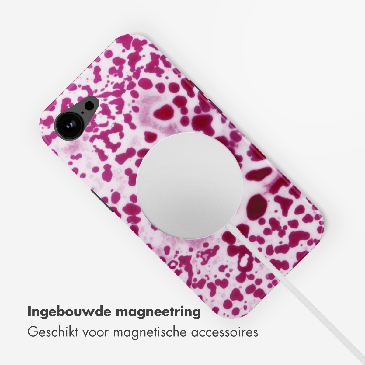 Un cavo di ricarica bianco è collegato a un telefono con motivo a macchie rosa.