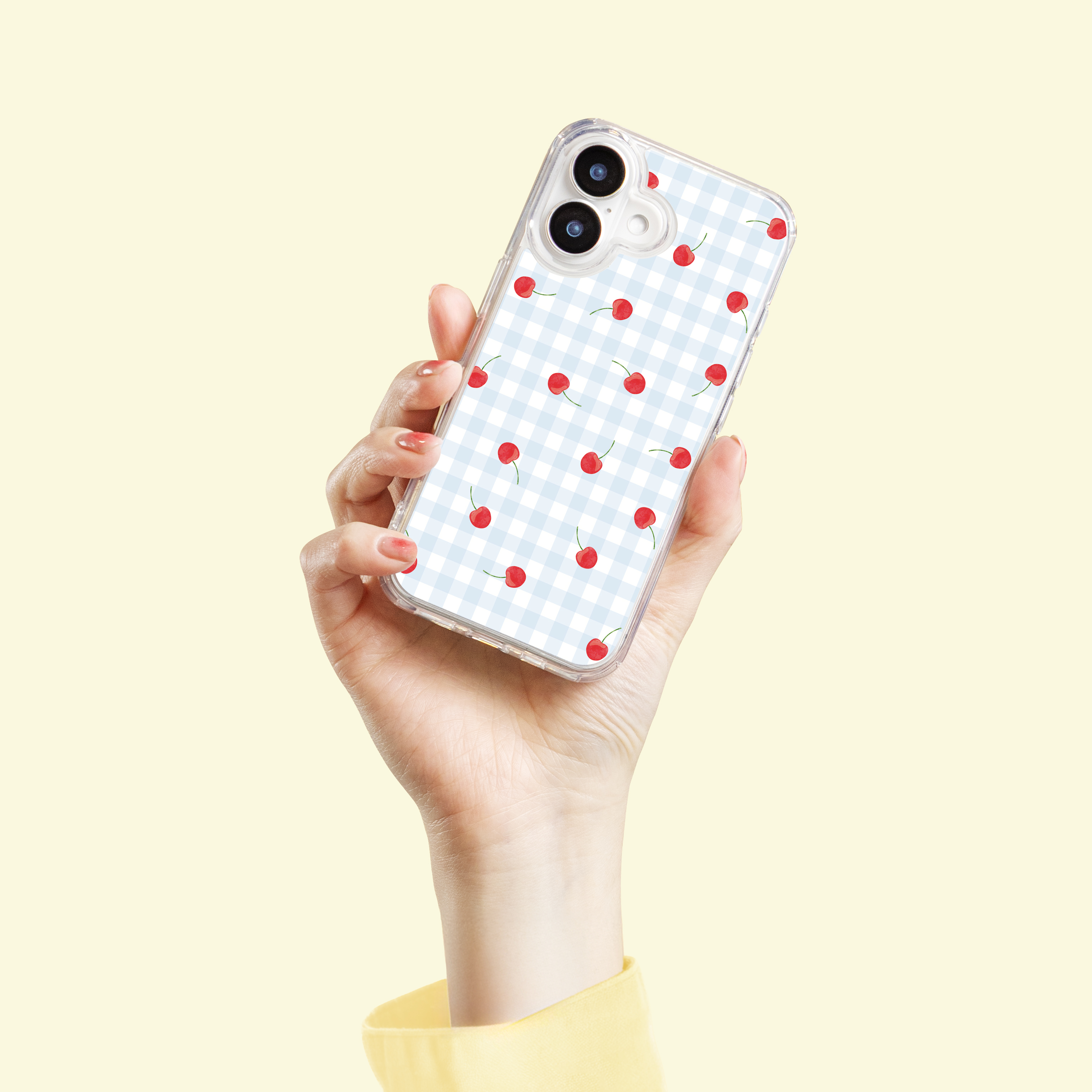 Hand houdt telefoon vast met blauw geruite hoes en kersenpatroon.