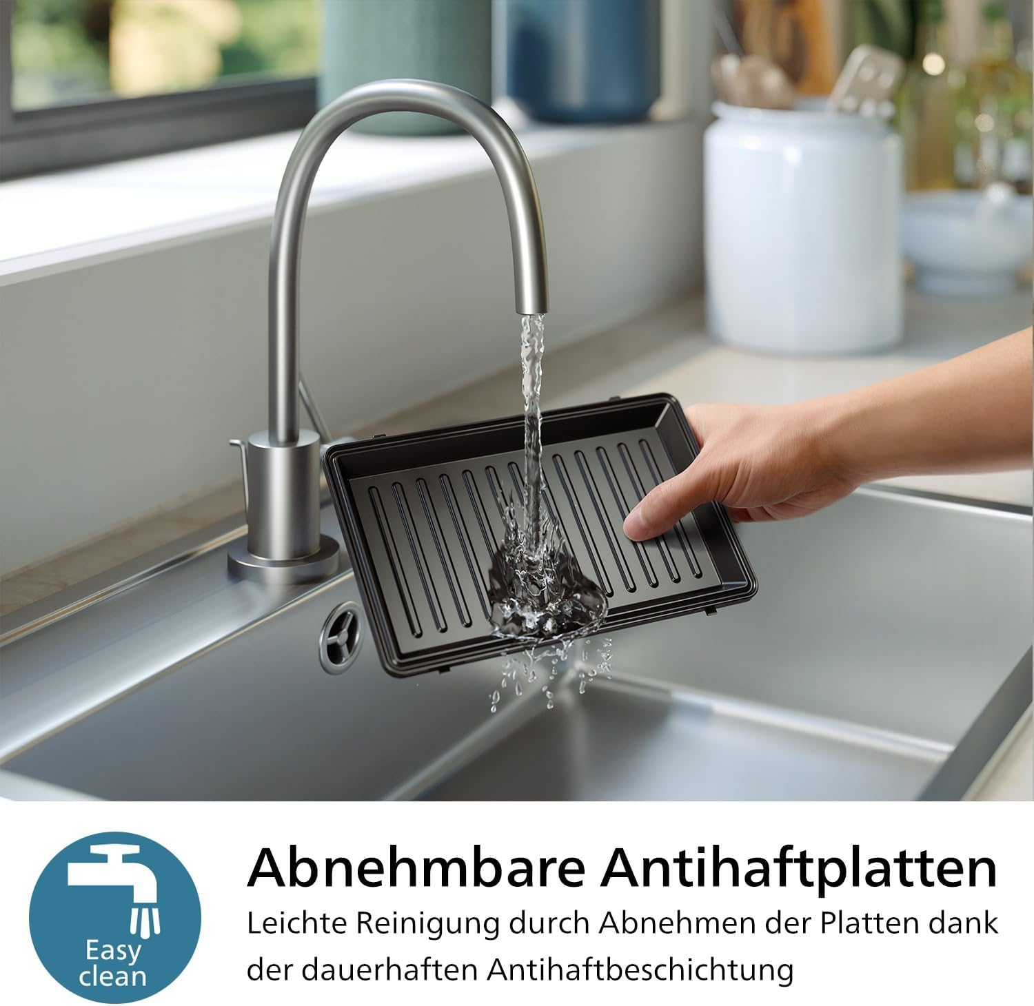 Eine Hand spült eine Grillplatte unter fließendem Wasser in einer Spüle.