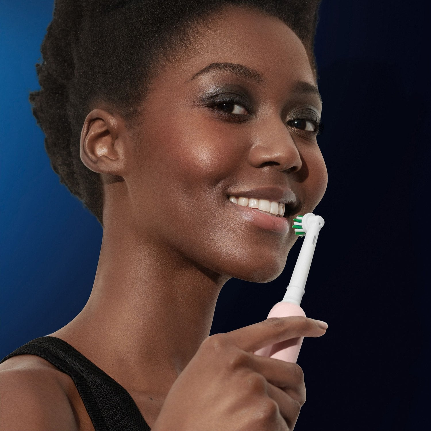 A woman is brushing her teeth with an electric toothbrush.