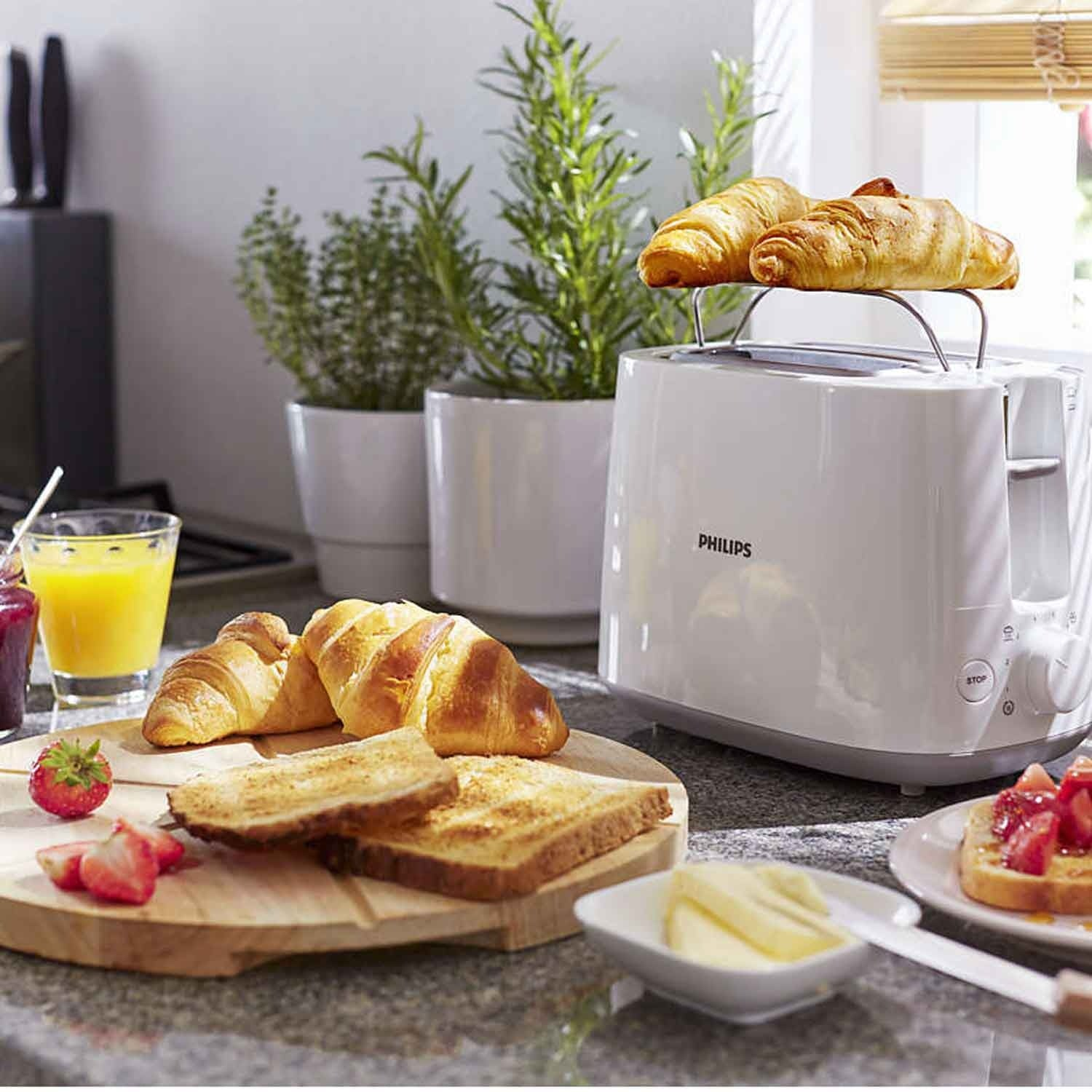 Een witte broodrooster met croissants, toast, aardbeien en sinaasappelsap.