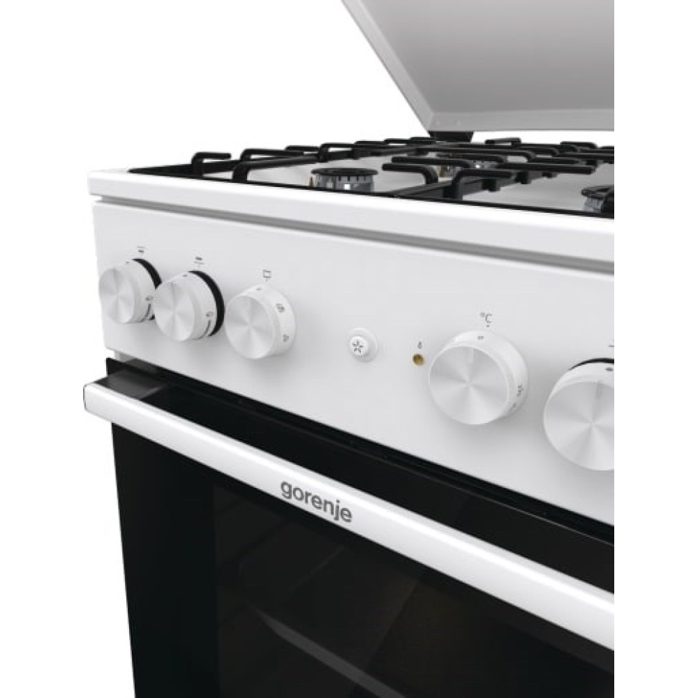 Zbliżenie panelu sterowania białej kuchenki gazowej z srebrnymi pokrętłami i czarnymi drzwiczkami piekarnika.