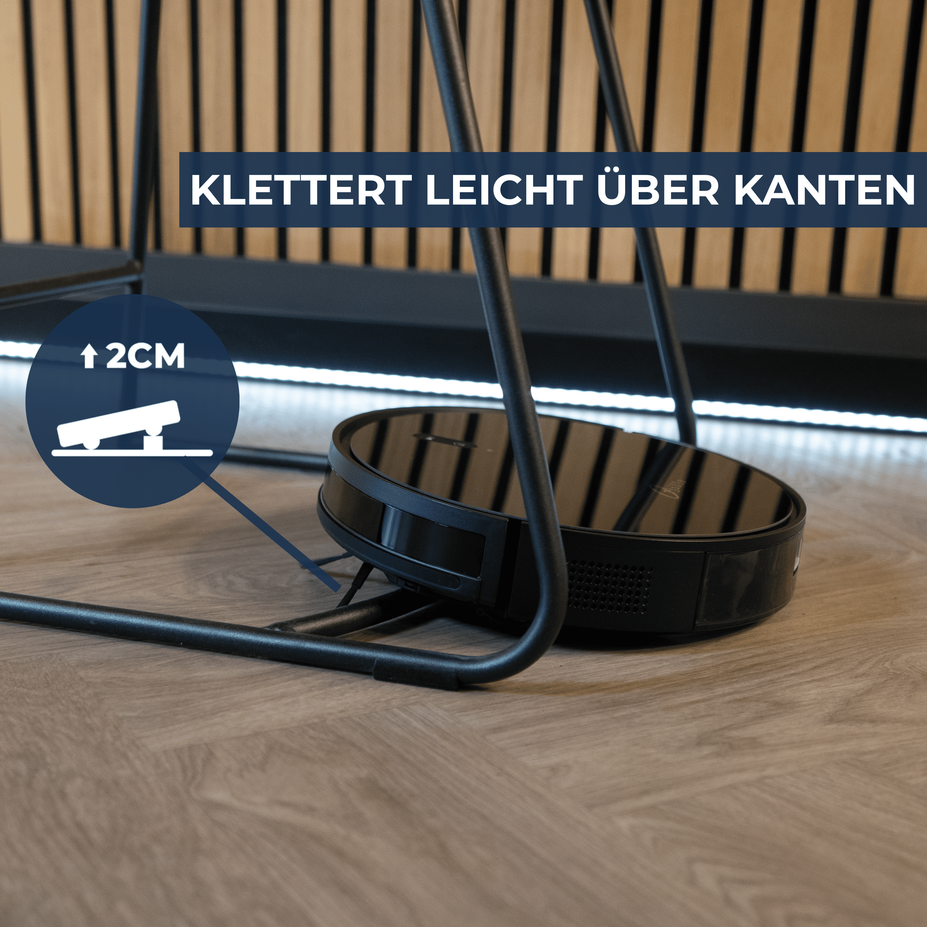 Ein schwarzer Saugroboter überquert mühelos eine Kante von 2 cm Höhe.