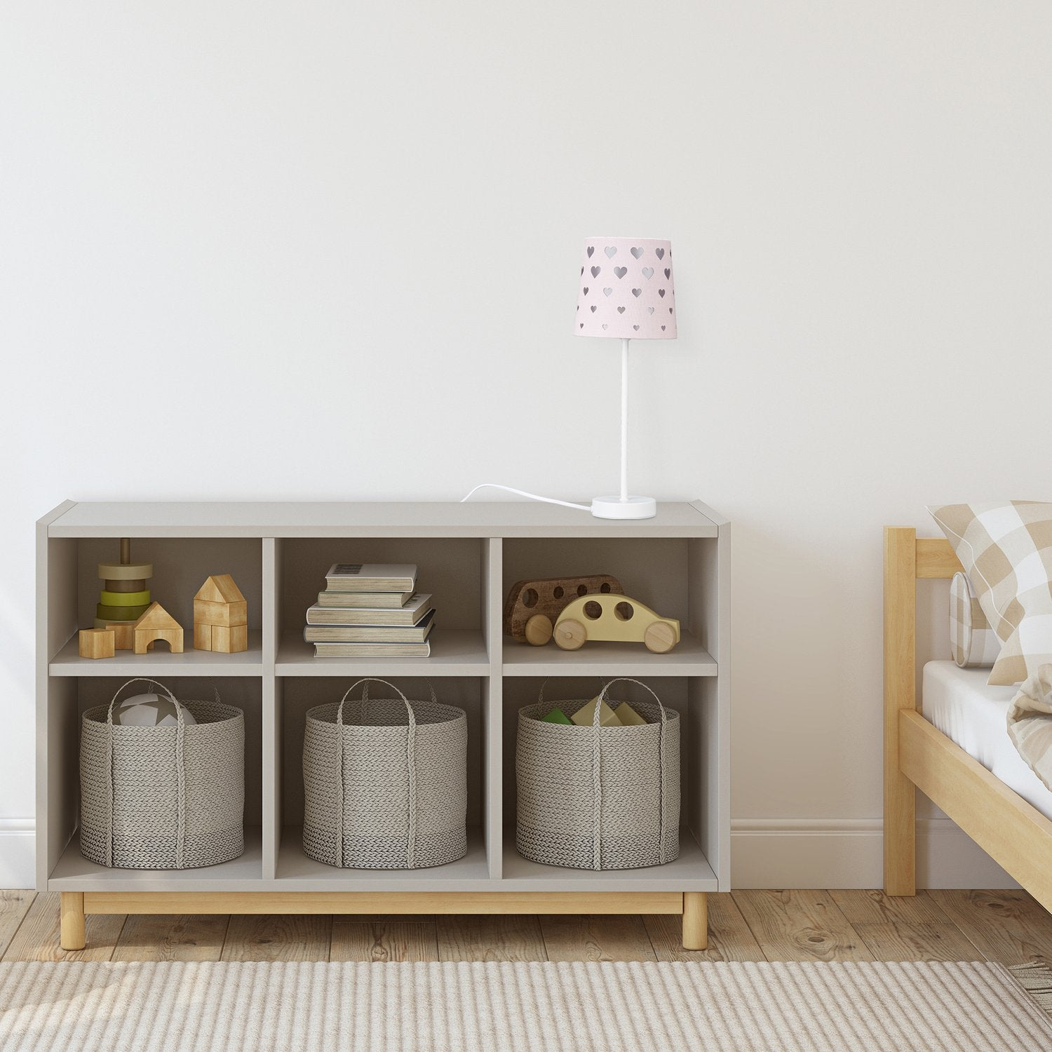 Habitación infantil con estantería llena de juguetes, cestas y libros. Una cama a la derecha.