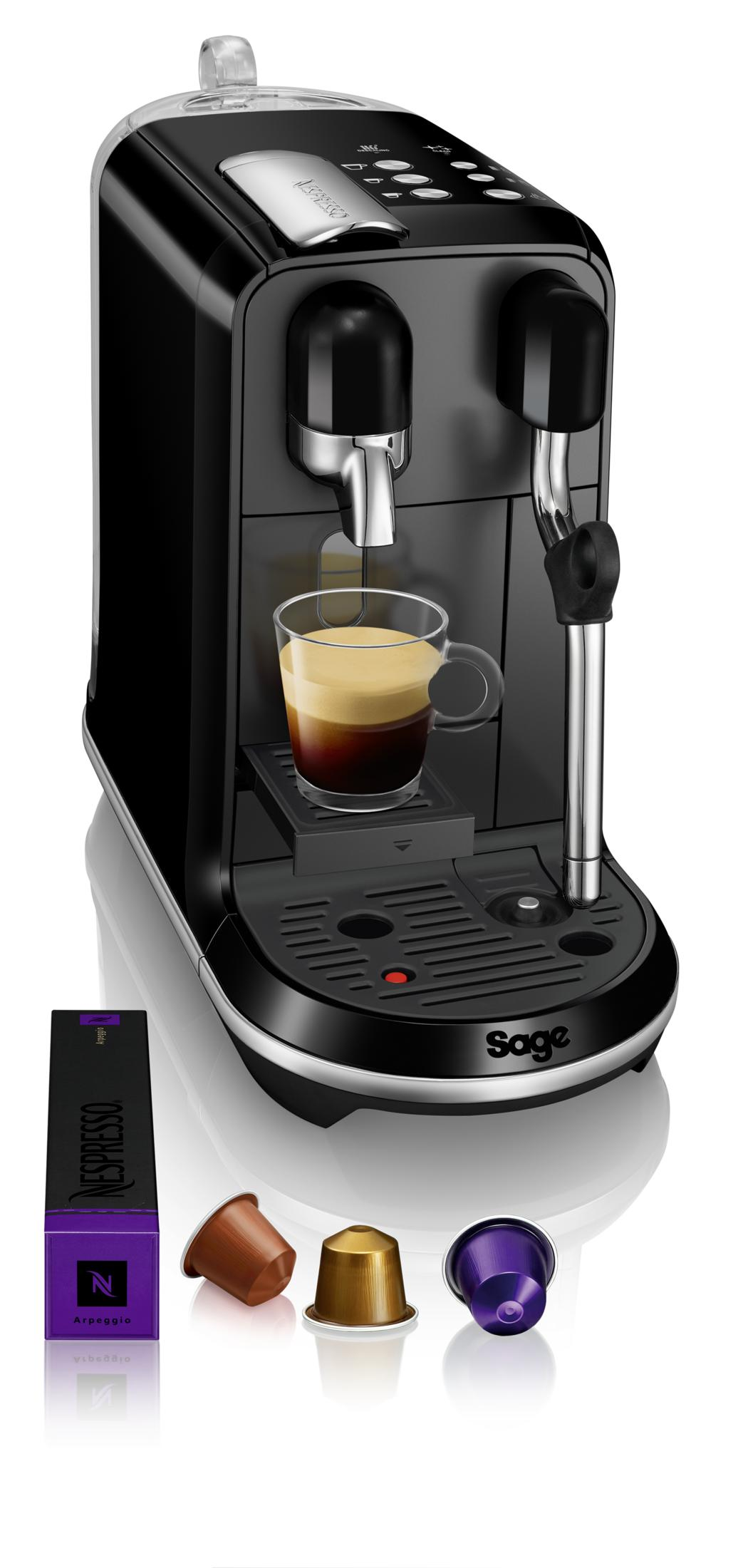 Schwarze Nespresso-Kaffeemaschine mit einer Tasse Espresso, Kapseln und Verpackung.