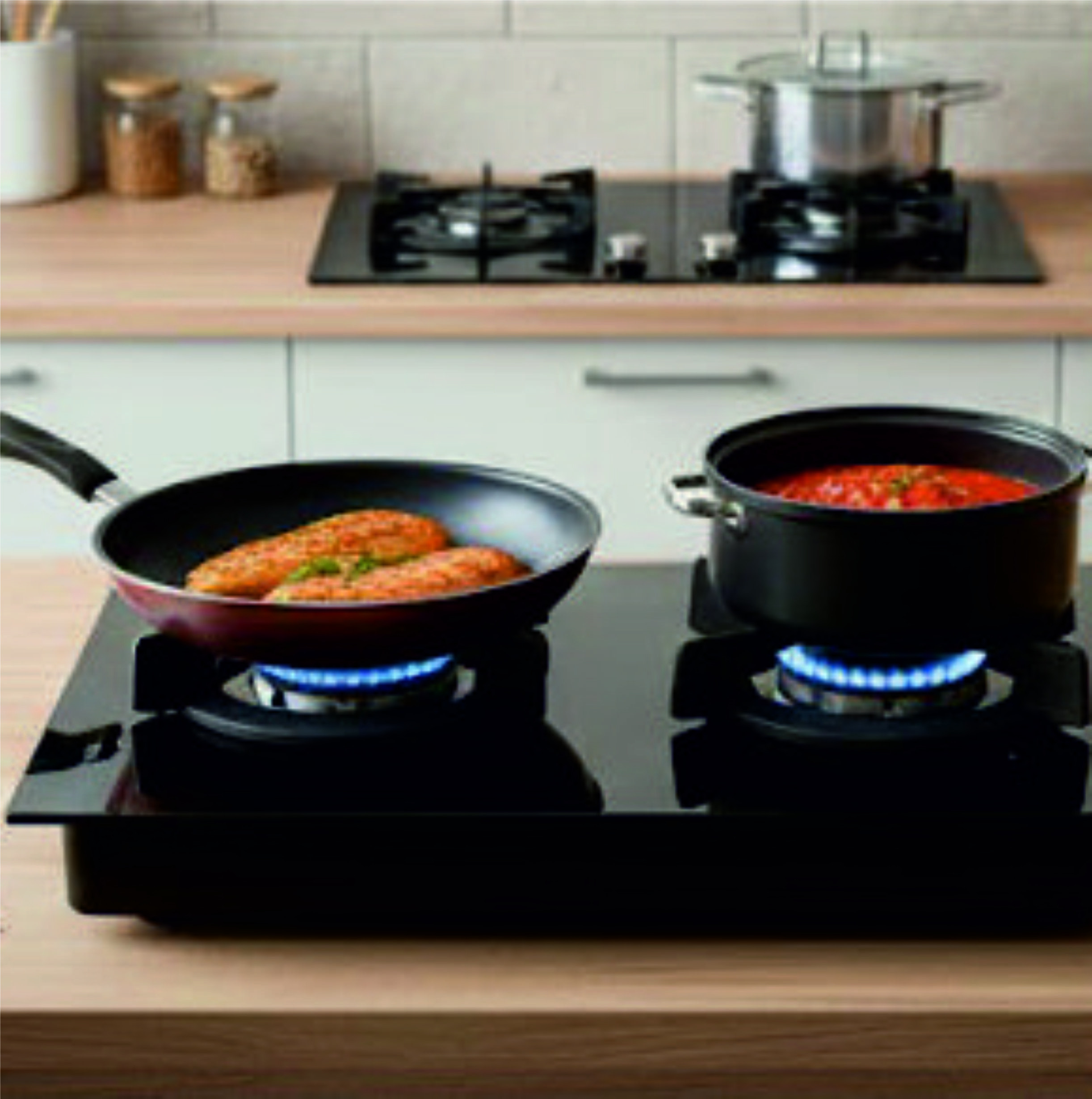 Dos ollas en una estufa de gas. Una fríe carne, la otra cocina salsa.